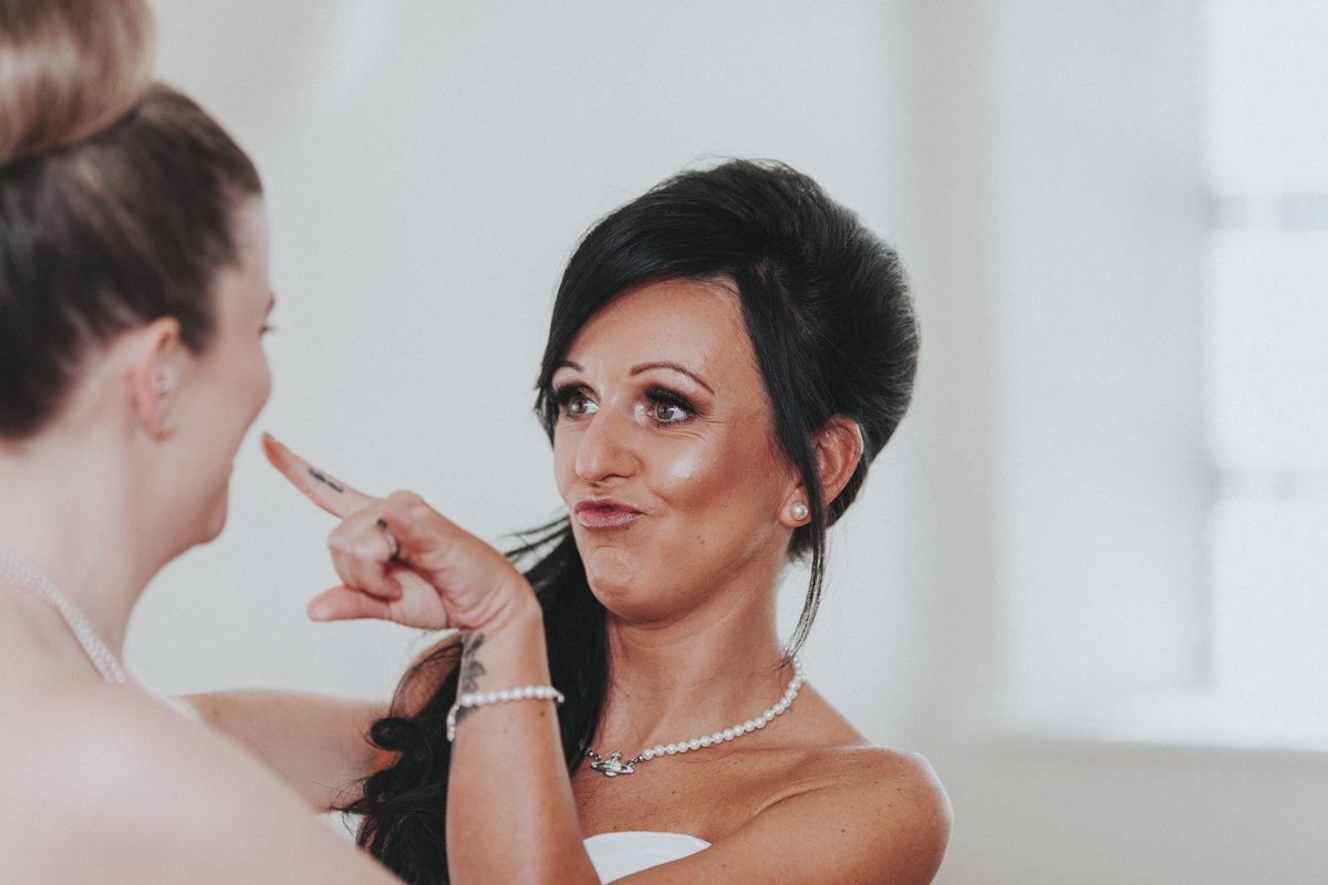 Bride poking finger at her bridesmaid before her Islington Town Hall Wedding.