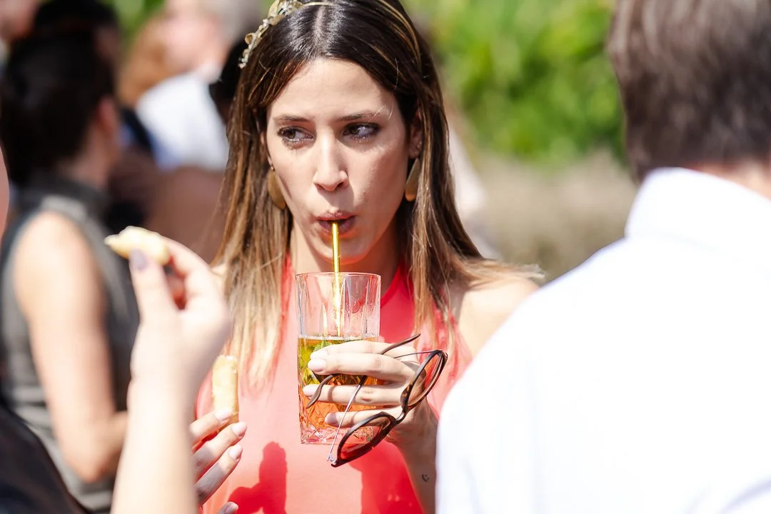 Guest with a glass of pimms enjoying her drink with a straw at a Hampton Court House Wedding.