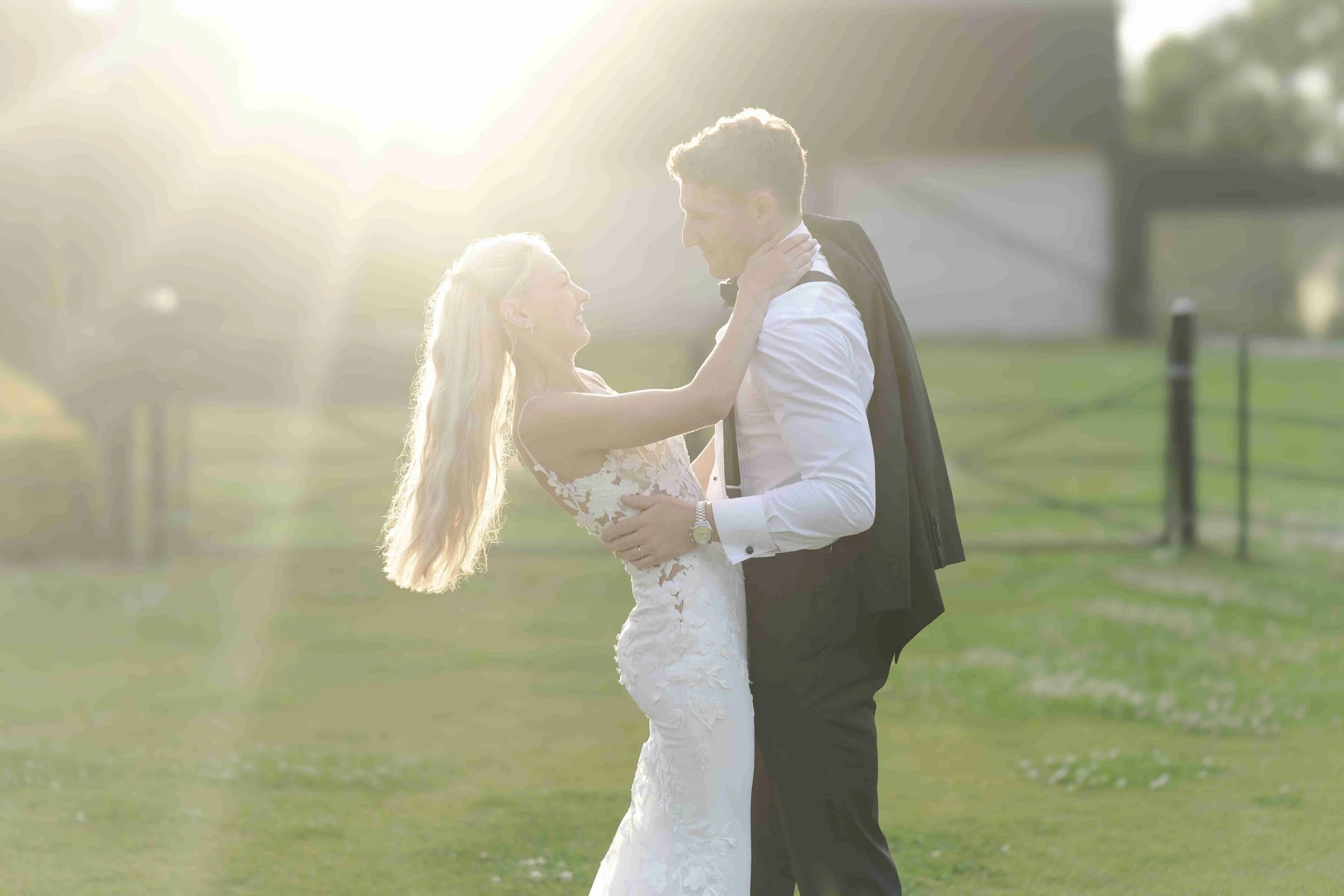 Couple facing and holding each other smiling with the groom's jacket sling over his shoulder at the Halfmoon Farm Wedding in Rutland