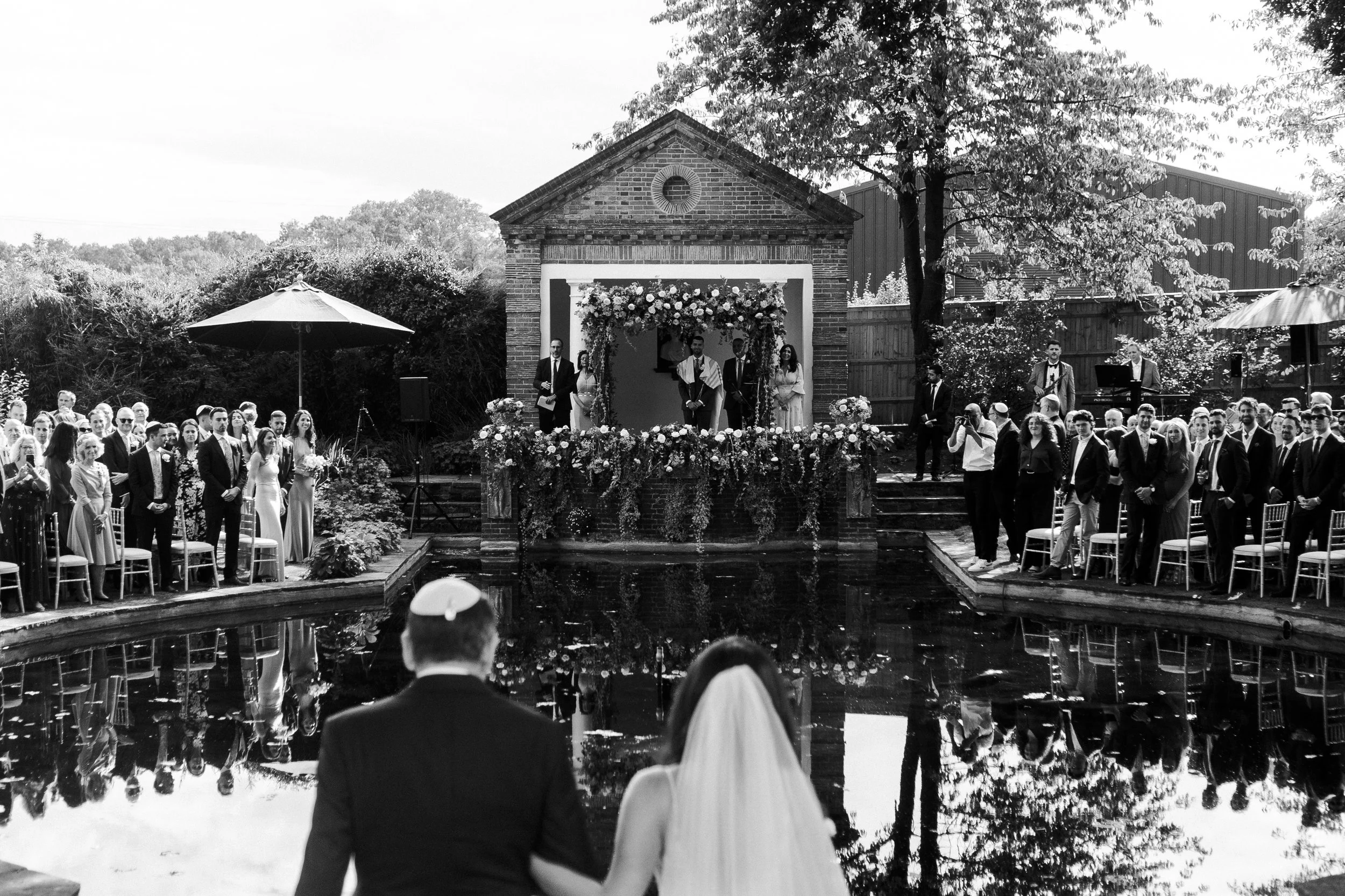 Bride with her father overlooking the pond at The Temple where the groom is standing at a Micklefield Hall Wedding