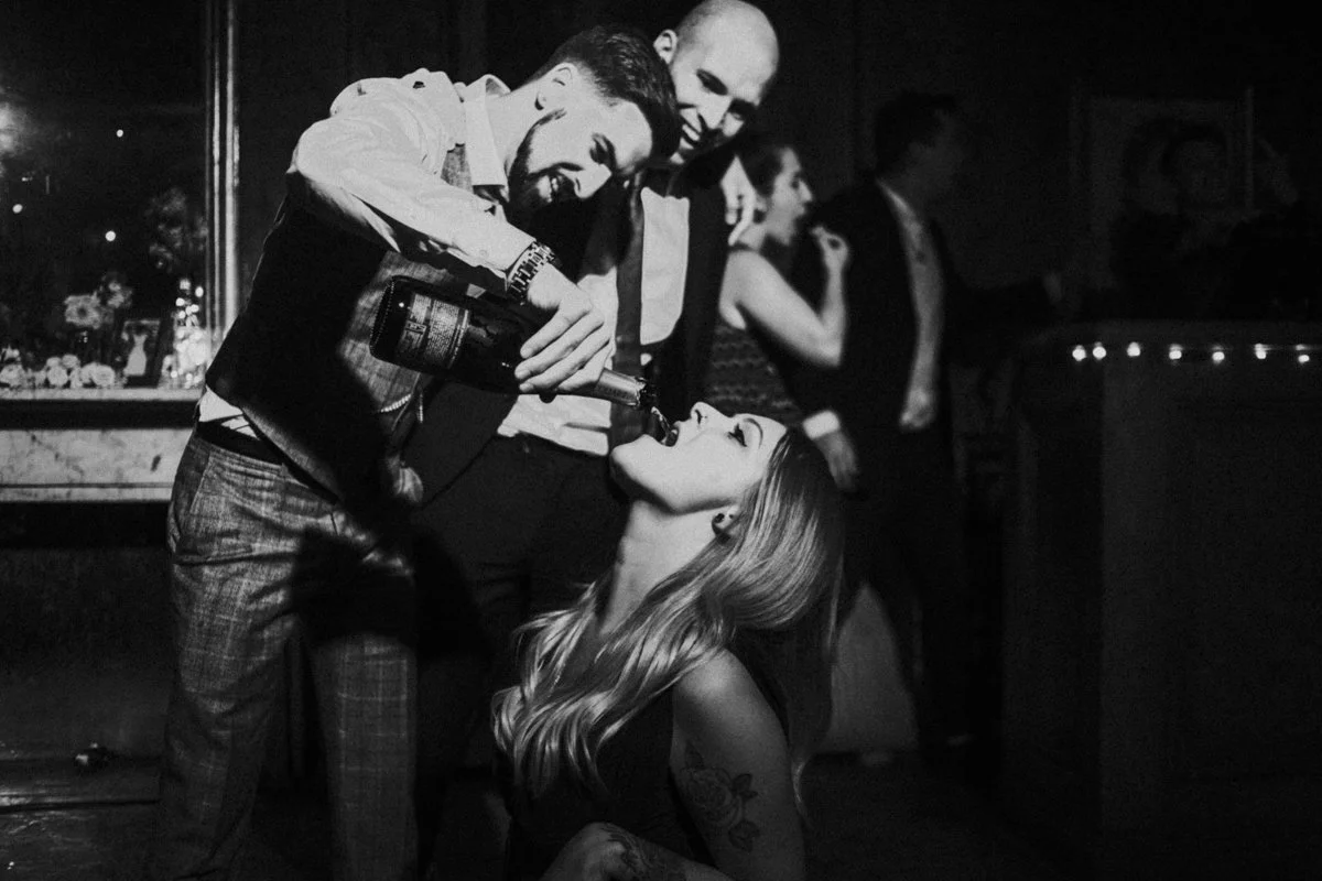 Groom pouring champagne down a guest throat straight from the bottle at the iconic The Old Queens Head, Essex Road, Islington at a London Wedding