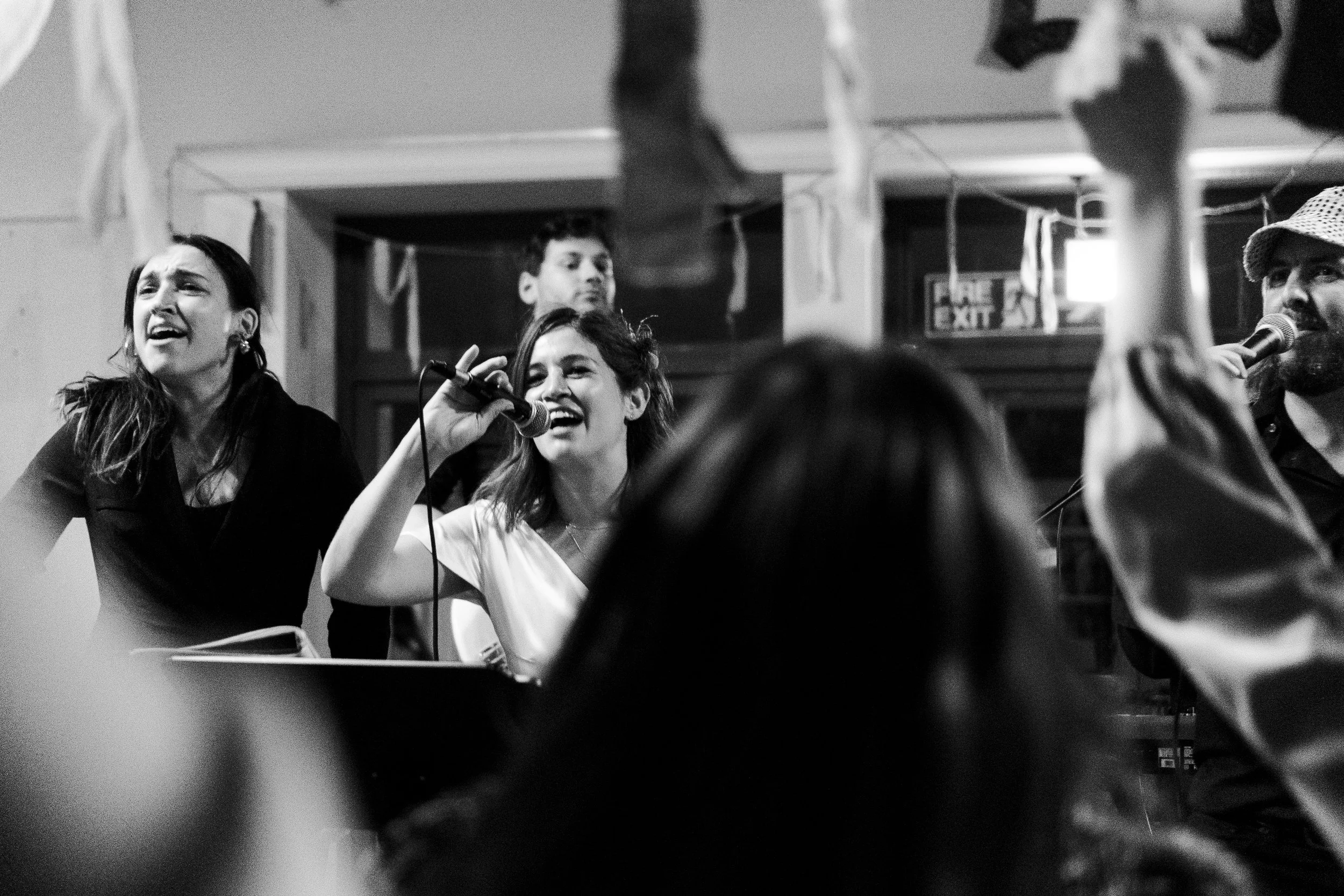 View through guest on the dancefloor of the bride singing on the stage at a Highgate, London Wedding.