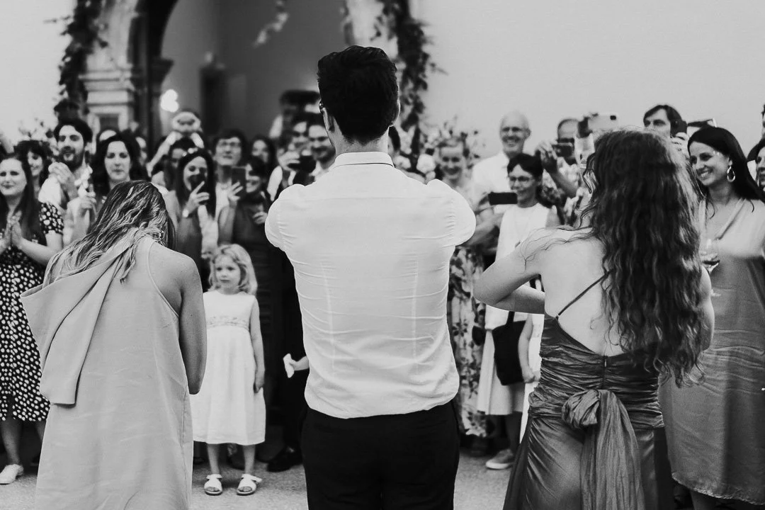 Guests on the dancefloor just finishing a dance routine are cheered by a crowd of guests at a Hampton Court House Wedding.