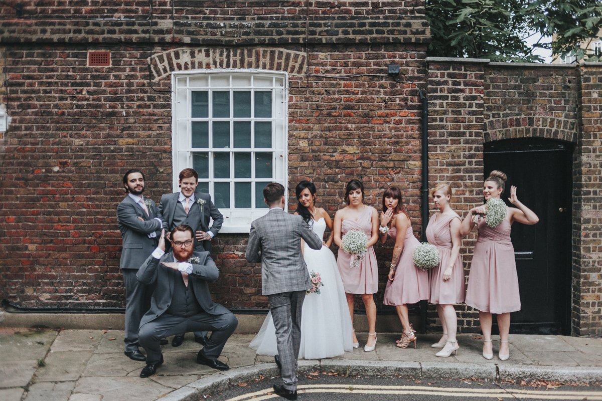 Bridal party doing funny poses against a wall near Islington Town Hall Wedding Venue