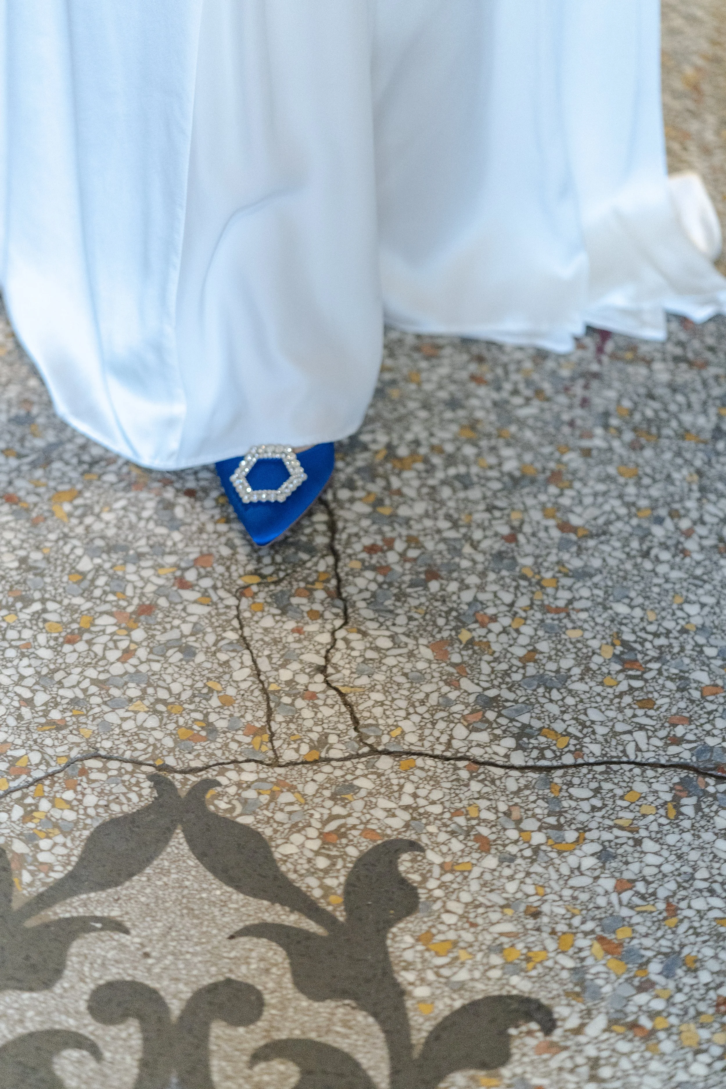 Bride walking over tiled flooring with just the bottom of her dress showing over a blue shoe at a Highgate, London Wedding