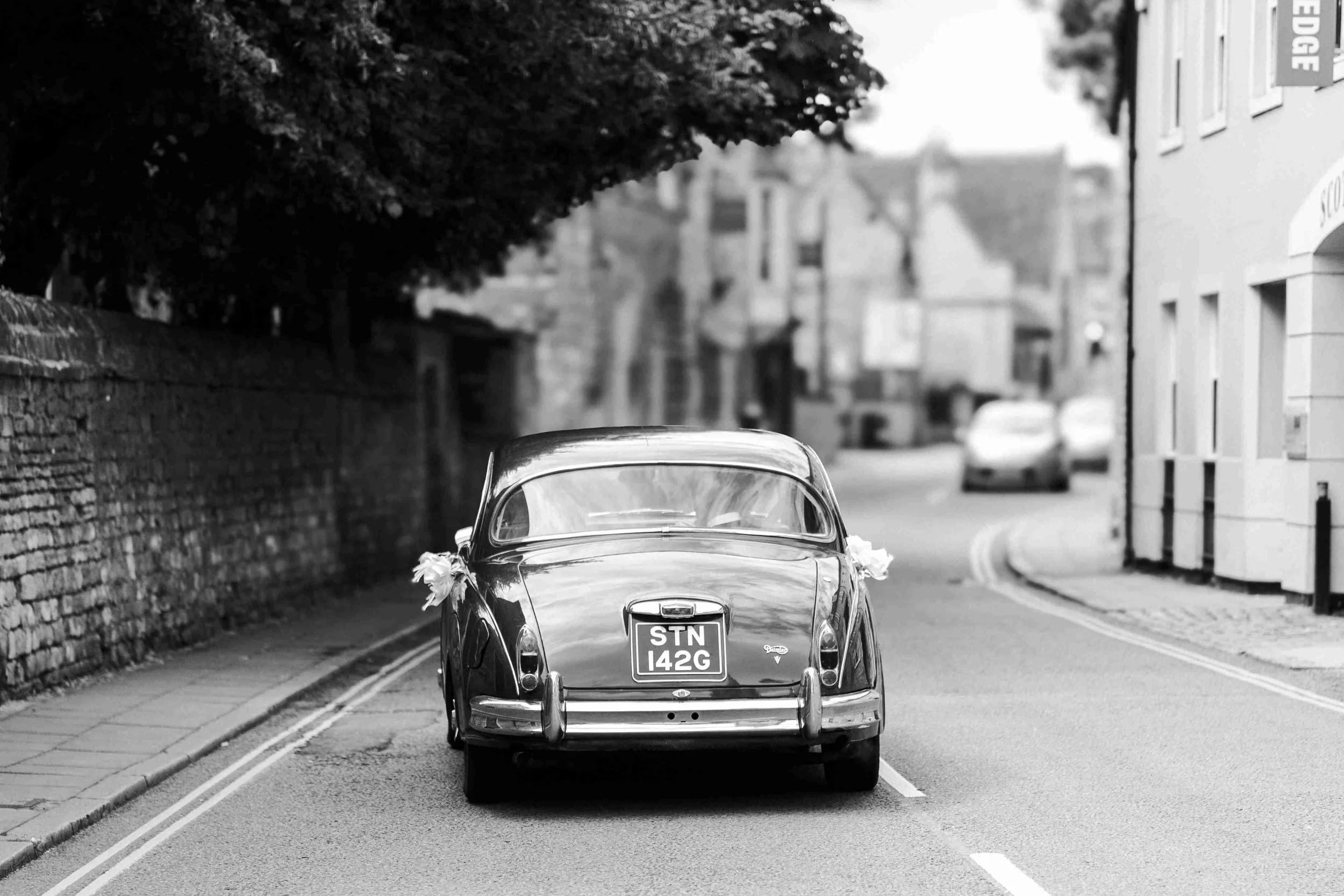 Wedding car being driven off to the wedding reception at the Halfmoon Farm Wedding in Rutland