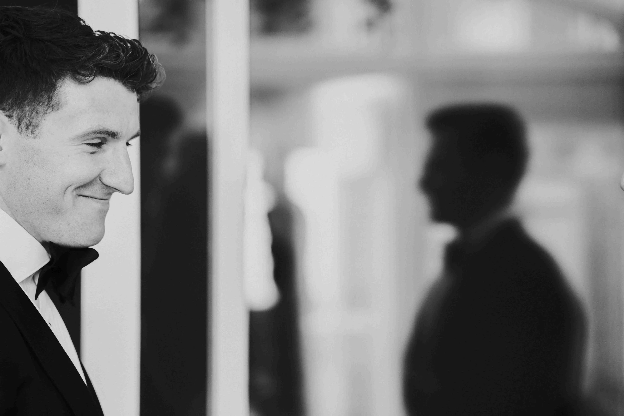 groom smiling with a silhouette of his groomsmen in the background before his Halfmoon Farm Wedding in Rutland