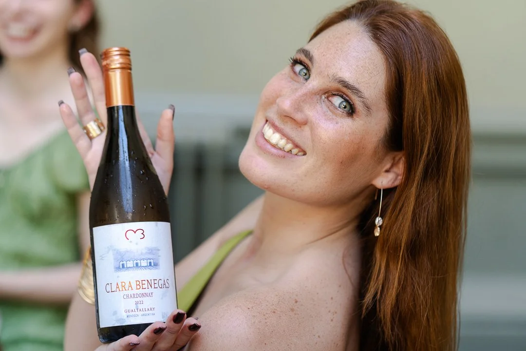 A guest smiling and presenting a bottle of wine at the dinner table at a Hampton Court House Wedding.