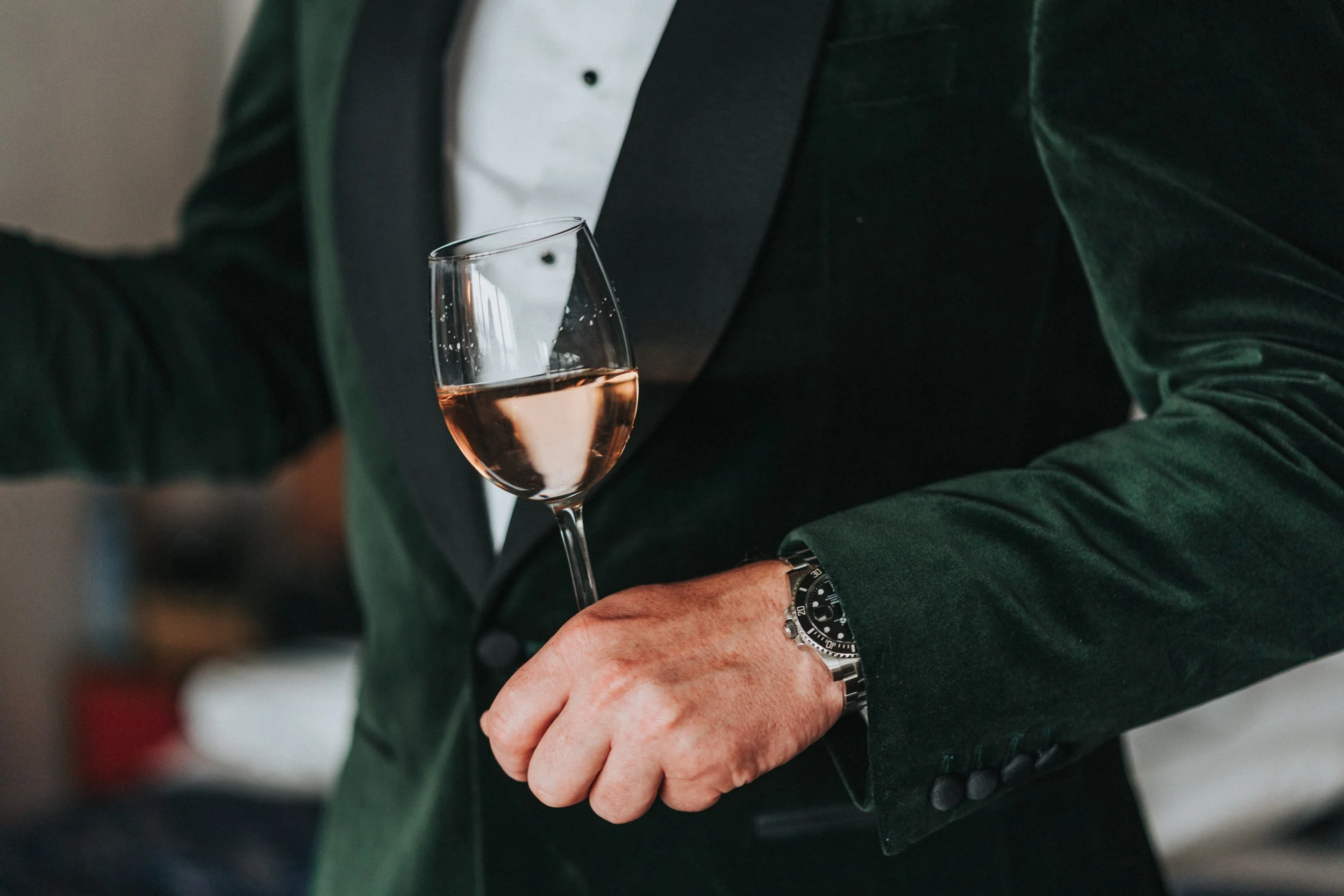 Groom holding a glass of wine with just his green toxedo jacket and white shirt in the image at a Old Marylebone Town Hall Wedding