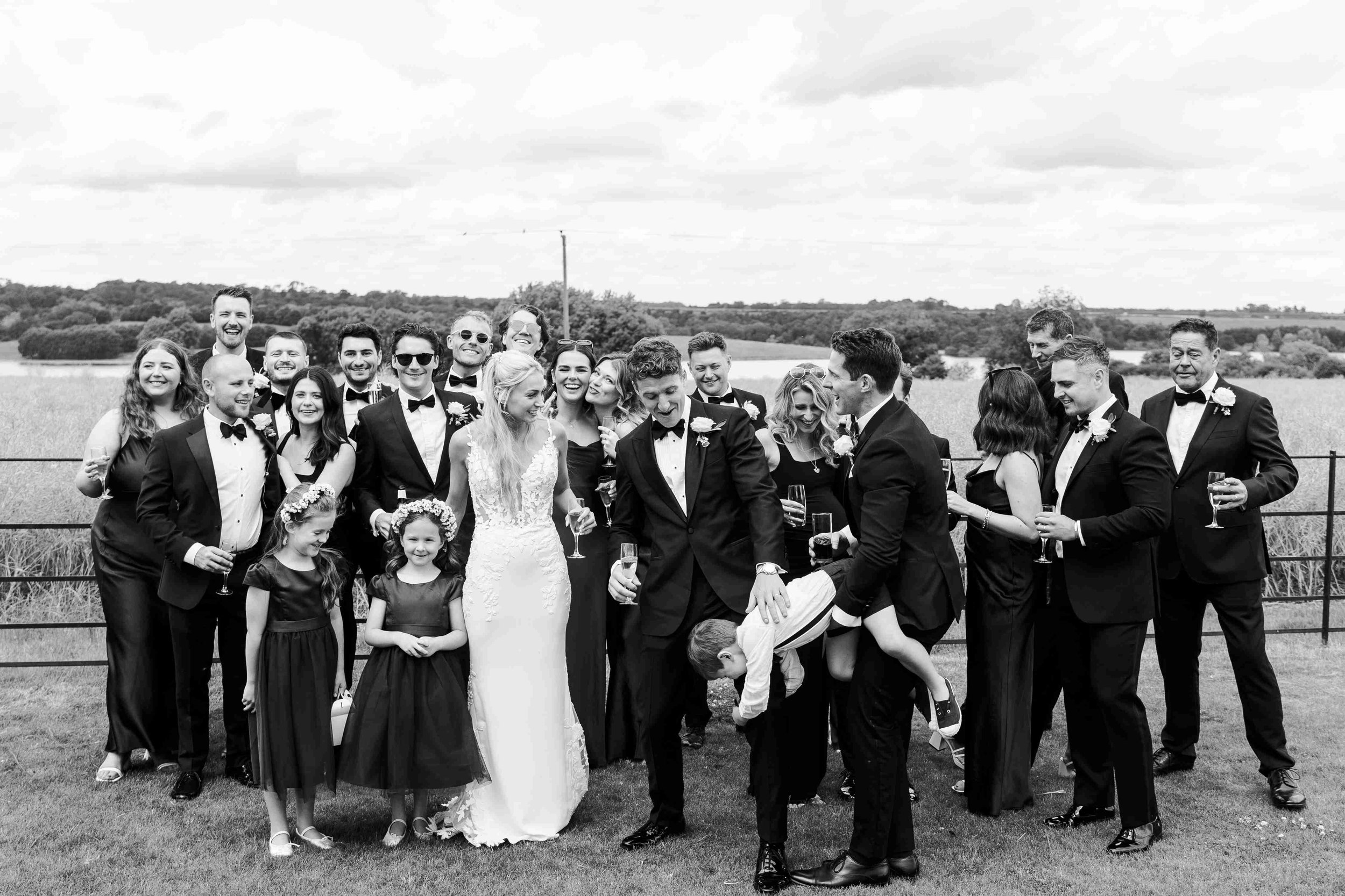 Funny group shot with the page boy being held upside by his father while other guests are laughing