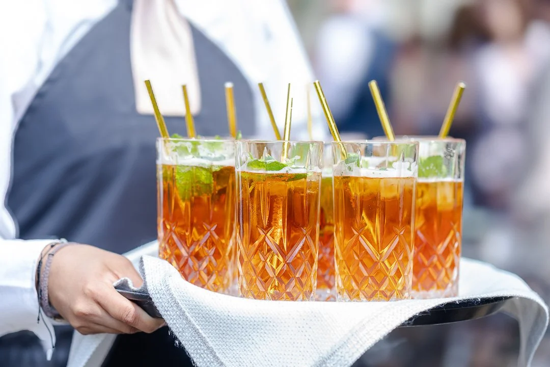 A waitresses with a tray of glasses of Pimms drink at a Hampton Court House Wedding.