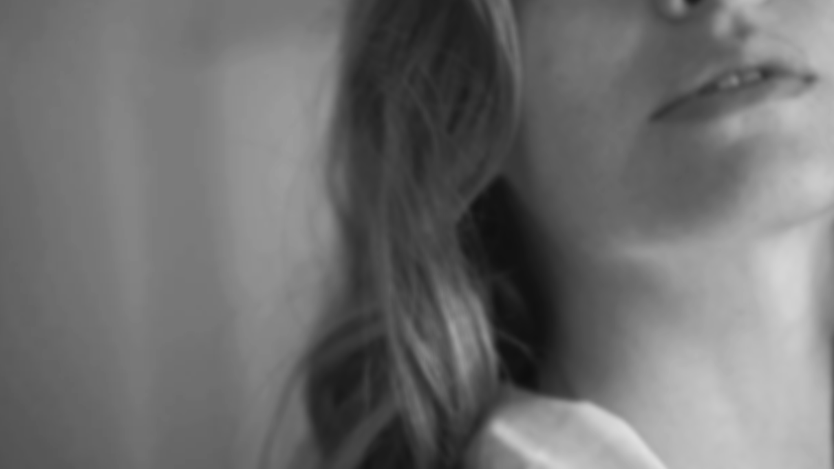 A partial black and white image of a woman's face, showing her lips, chin, and part of her hair.