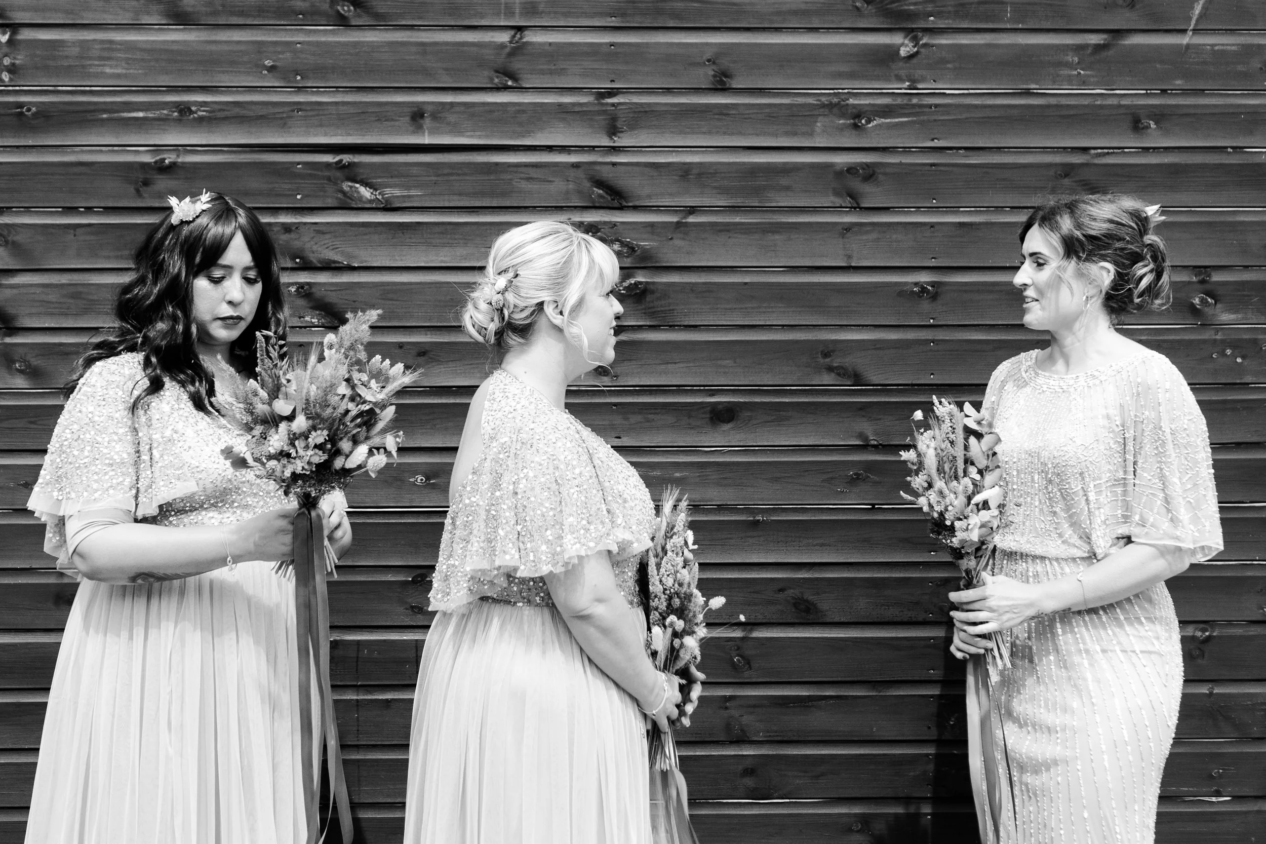 bridemaids lined up and chatting outside the ceremony barn at a rhyse farm wedding