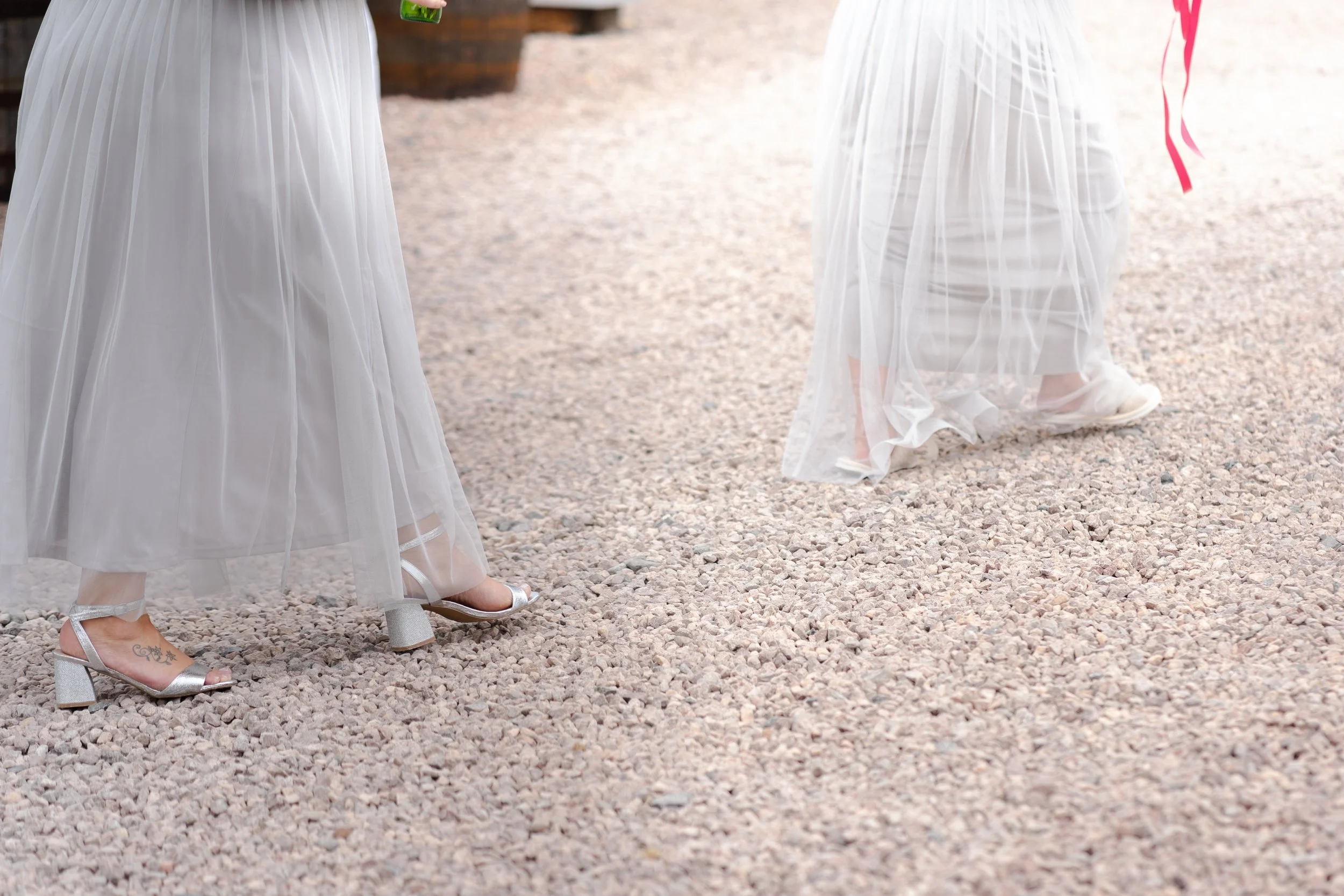 Image of Bride and bridemaids legs walking over gravel at a rhyse farm wedding