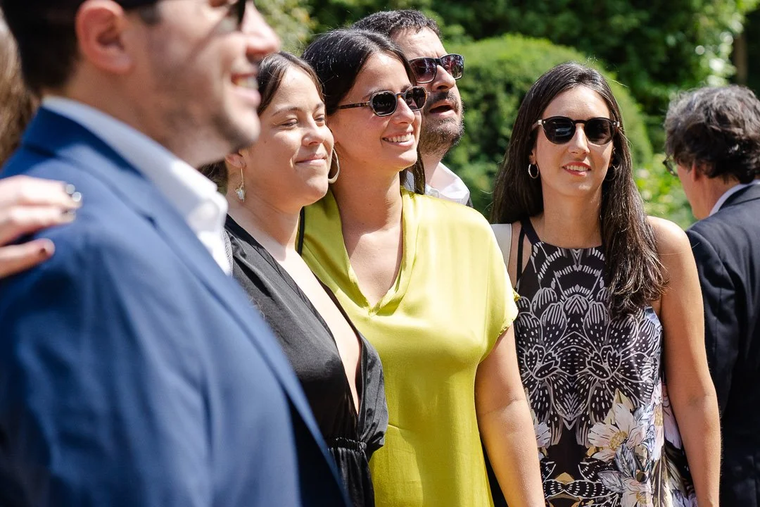 Guests wearing sunglasses standing and posing for a photograph outside Hampton Court House at a London Wedding.