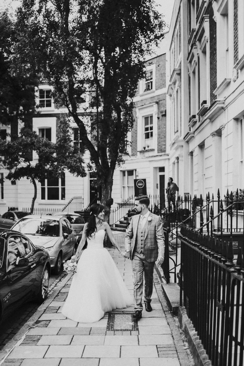 Bride & Groom walking down a street and looking at each other near Islington Town Hall Wedding Venue
