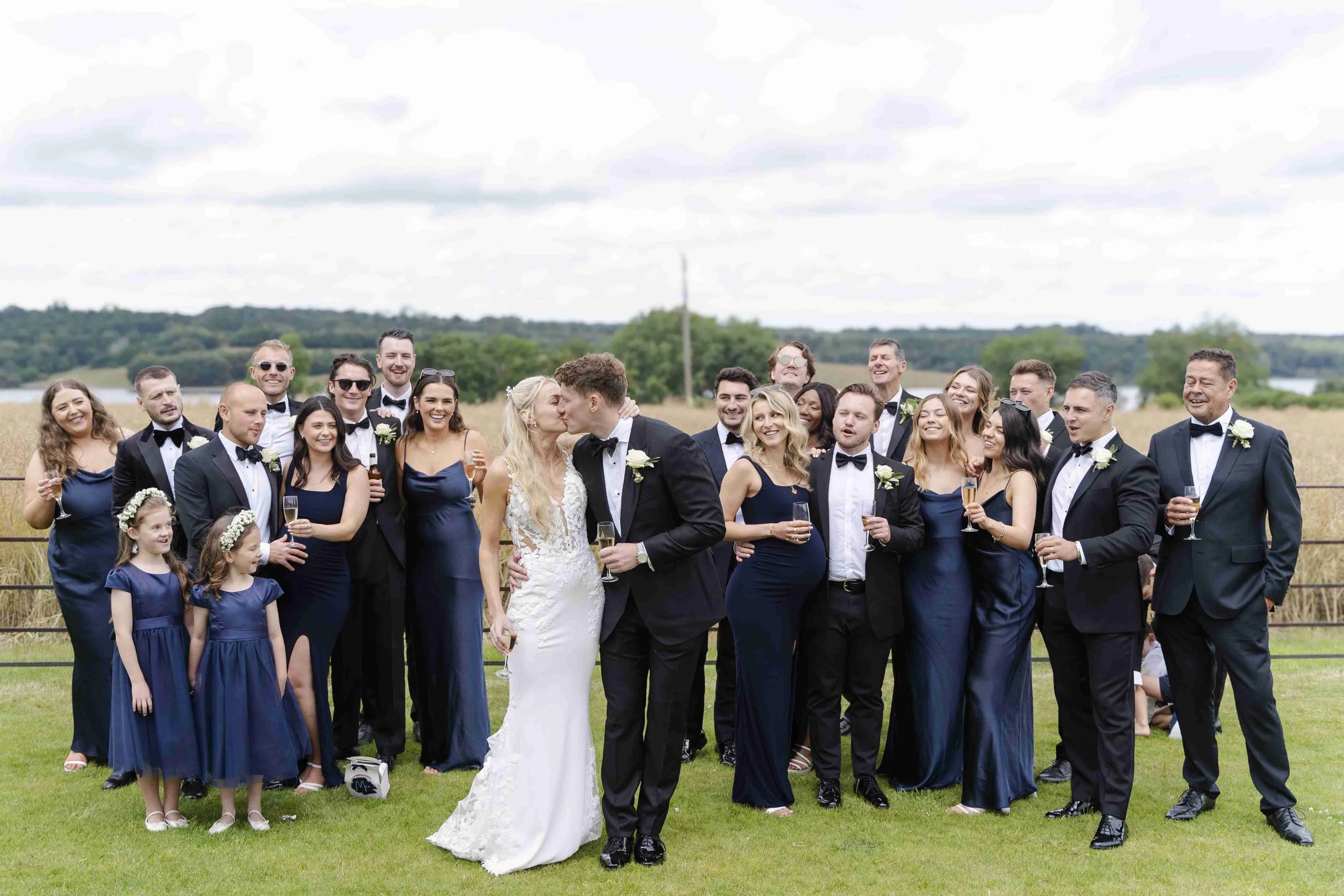 Friends gathering around the couple while they kiss at the Halfmoon Farm Wedding in Rutland