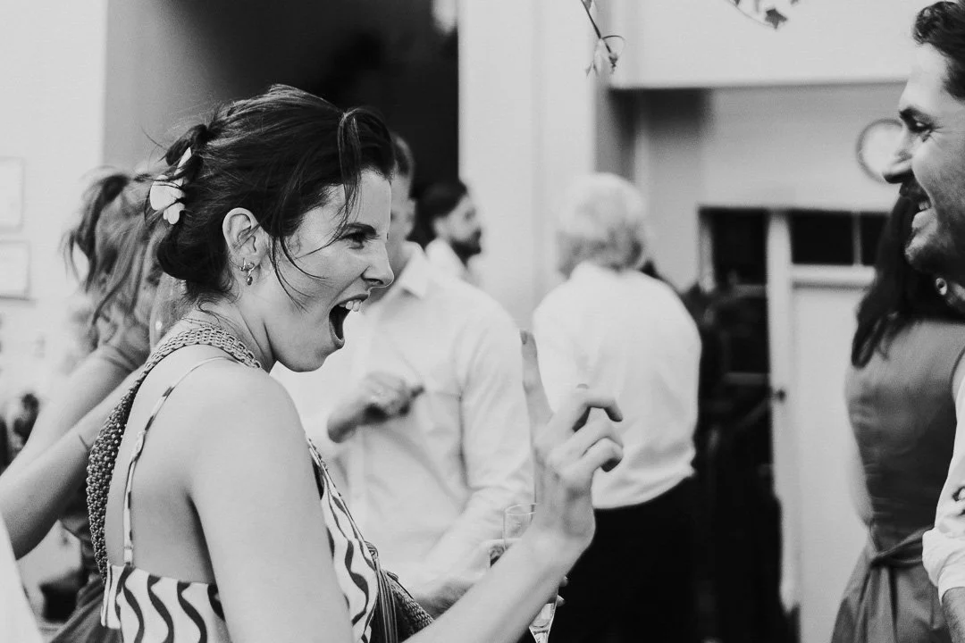 A guest dancing, mocking a lion roar with her face and hands at a Hampton Court House Wedding.