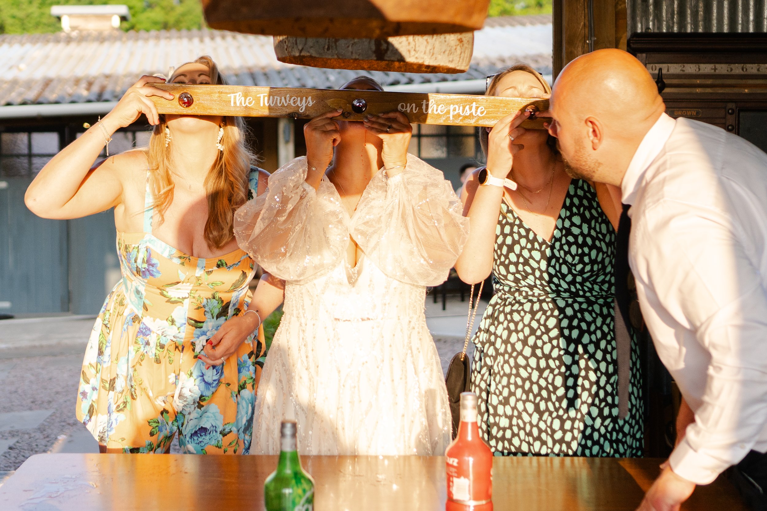 Bride & Wedding guests drinking shots from a snow ski with the evening sun shining at a rhyse farm wedding