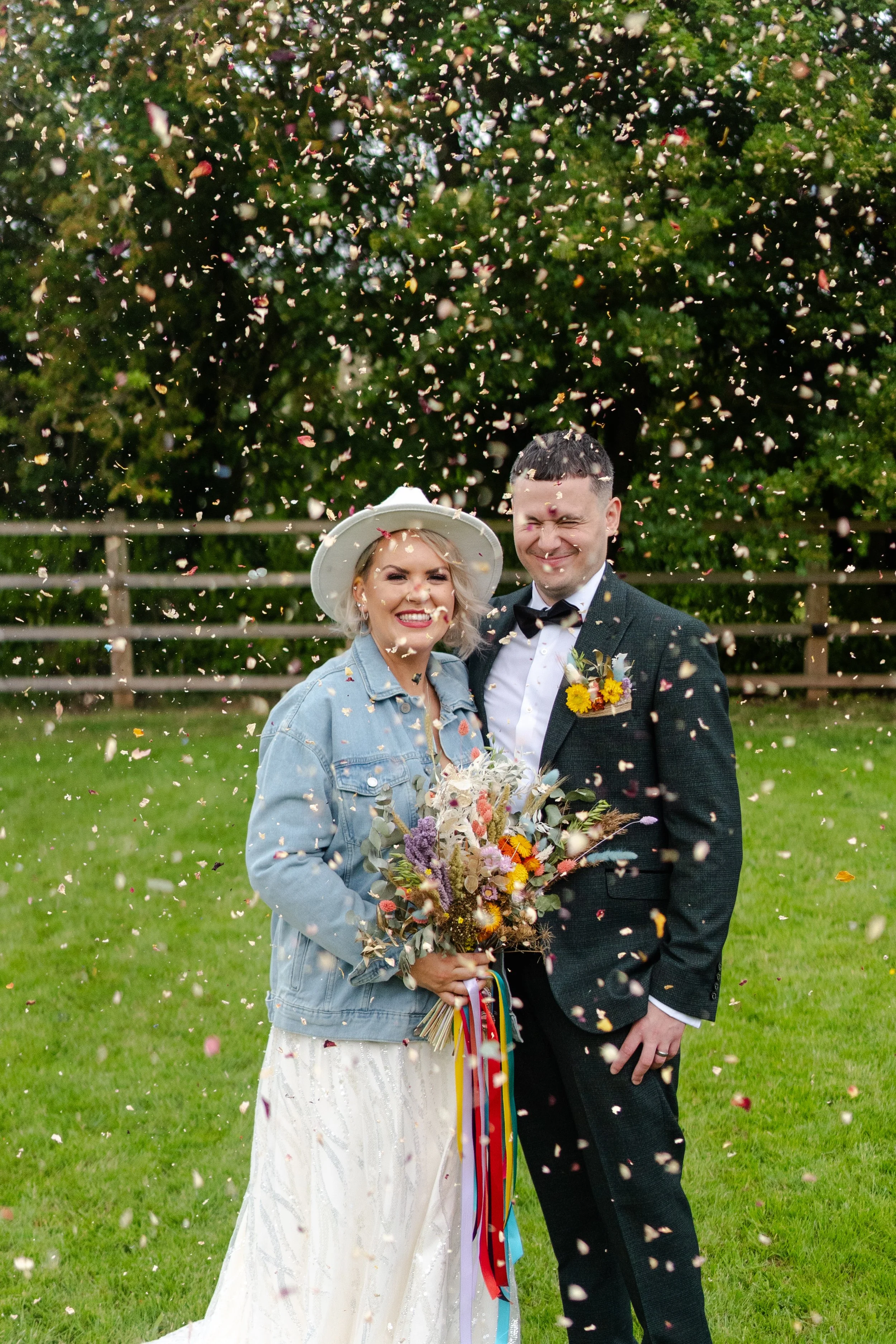 Wedding couple standing together while they are showered with confetti at a rhyse farm wedding