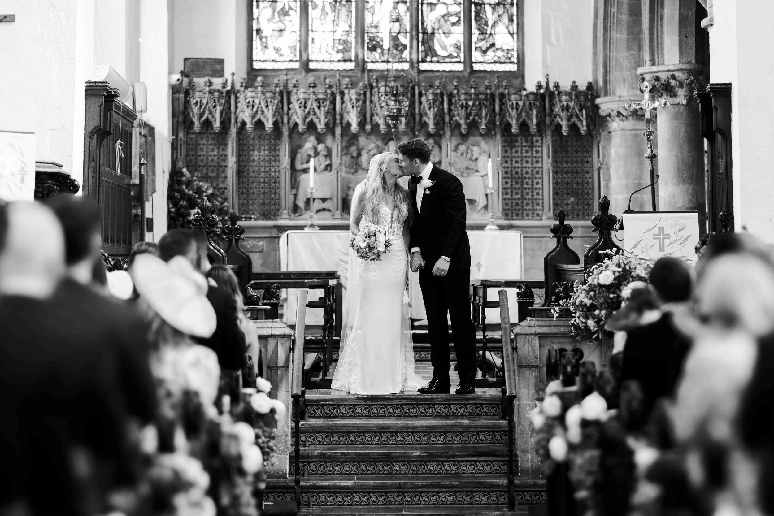 Couple in the front of their guests at the altar of the church having a kiss at the Halfmoon Farm Wedding in Rutland