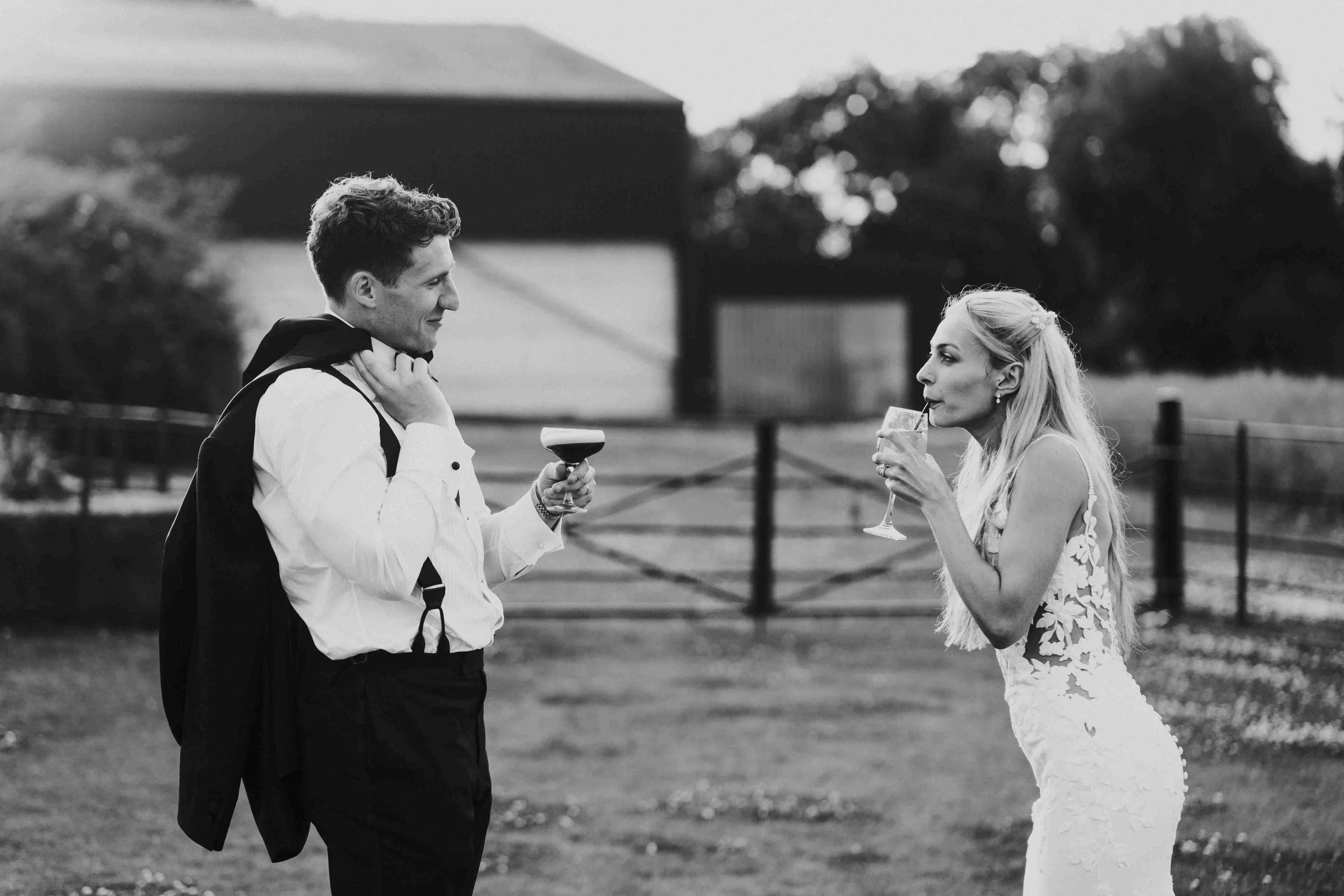 Couple facing each other while the groom holds his cocktail the bride is taking a sip at the Halfmoon Farm Wedding in Rutland
