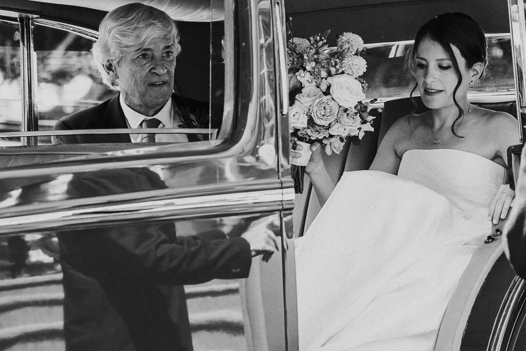 Bride and her Father preparing to leave the wedding car with a reflection of the driver in the car bodyworks at a Hampton Court House Wedding