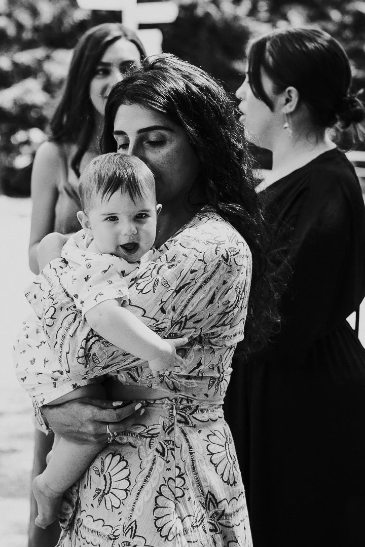 Guest holding a baby in her arms with the baby smiling and looking at the camera at a Hampton Court House Wedding