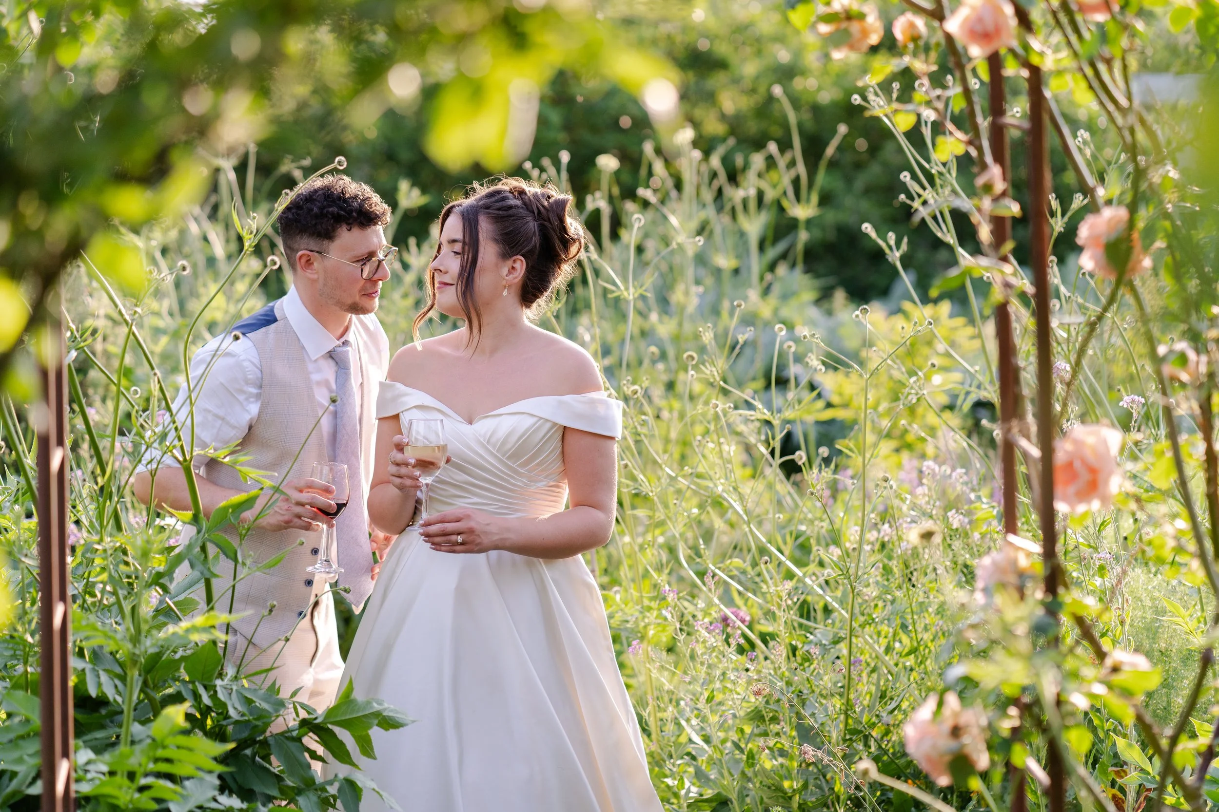 Bride & Groom walking through a flower garden looking at each other at a Worton Kitchen Garden, Oxfordshire Wedding.