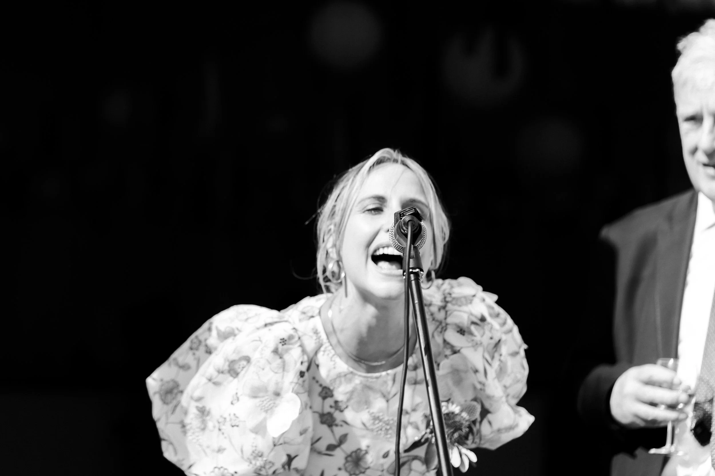 Groom's Sister leaning into the microphone to make an announcement at a Highgate, London Wedding.