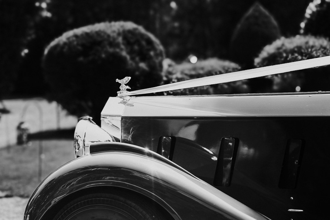 A view of the Rolls Royce car from the side wuth the iconic lady with wings emblem at a Hampton Court House Wedding