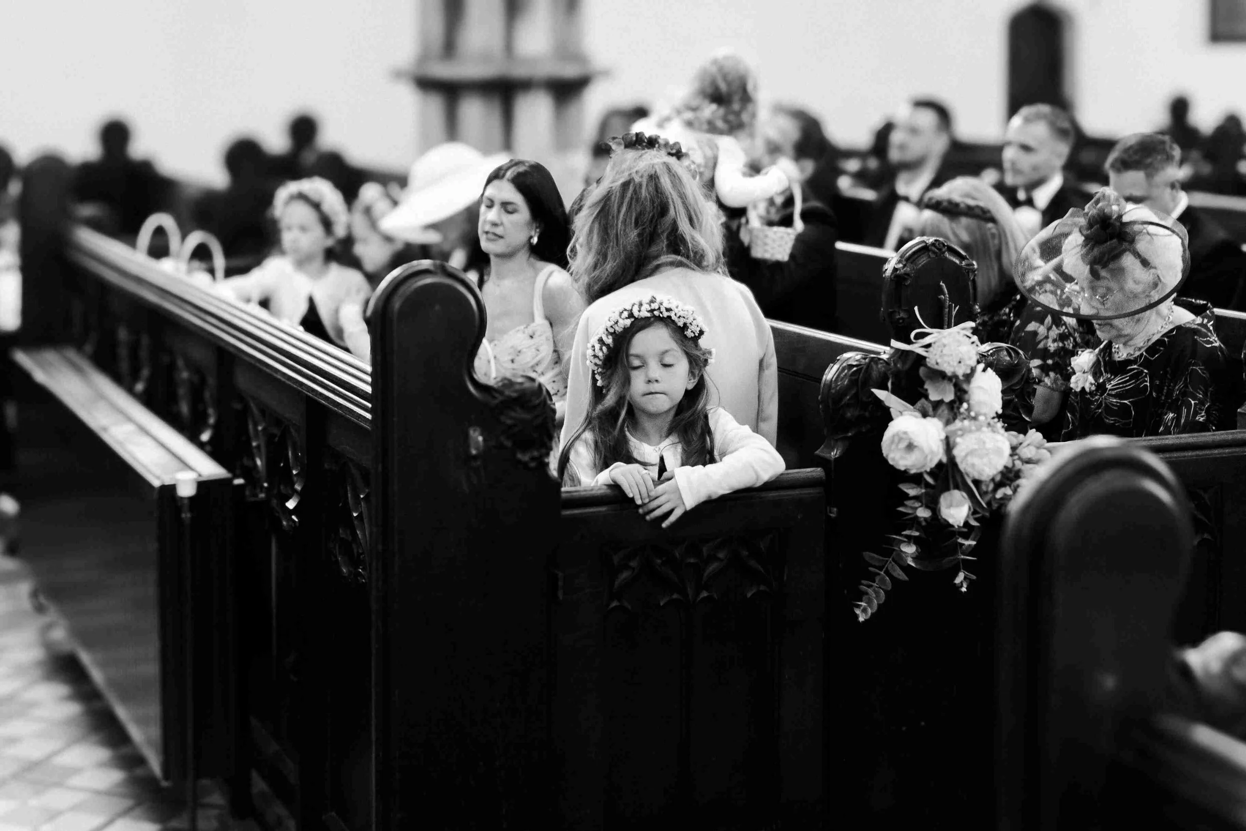 Flower girl in the pews with her eyes closed at thethe Halfmoon Farm Wedding in Rutland