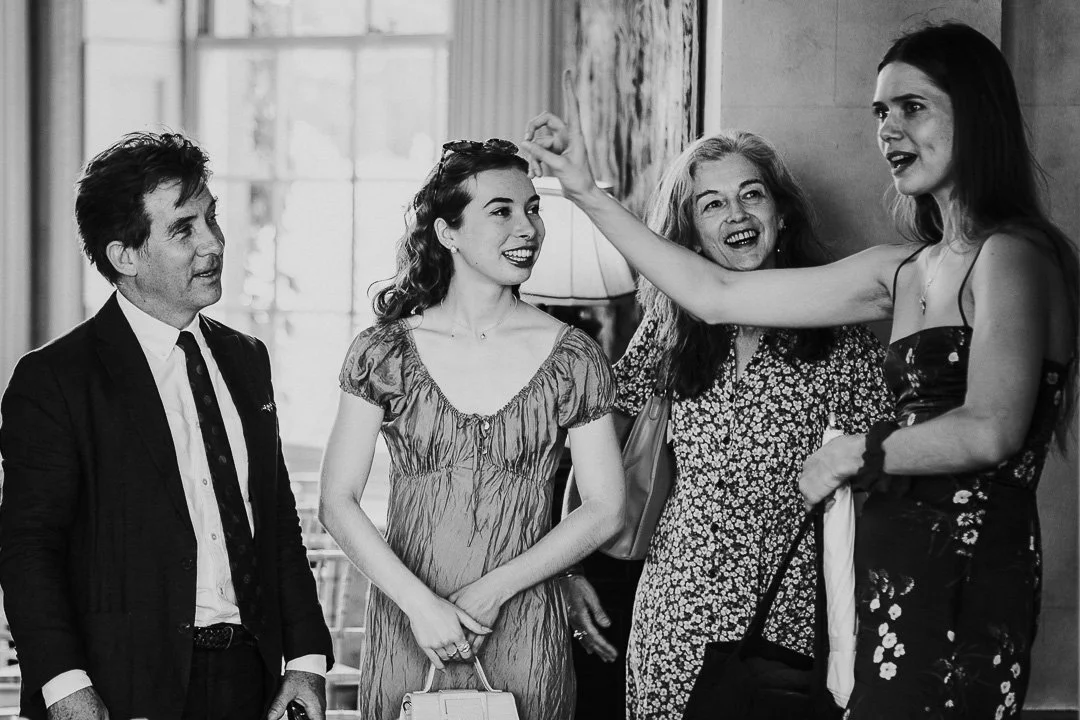 Four guests standing together at a Hampton Court House, with one animately telling a story.