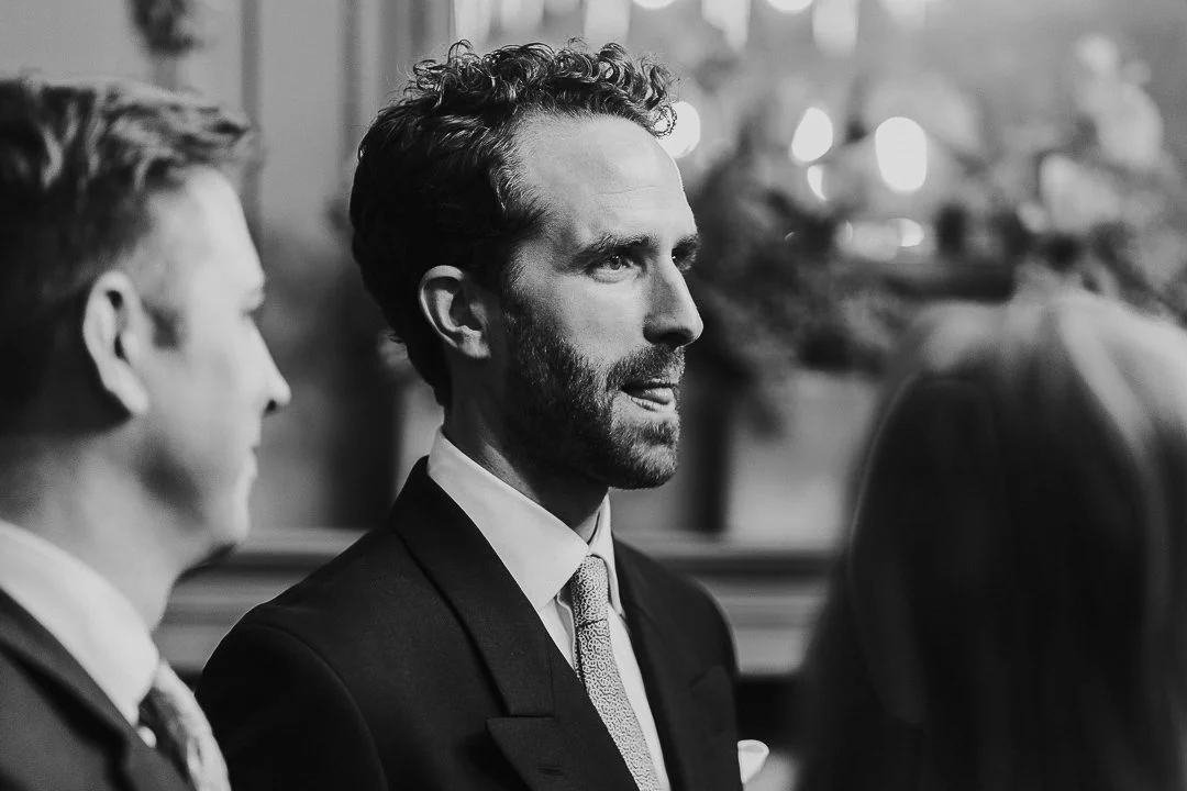 Groom staring ahead with his tongue poking out a bit in the ceremony room at the Old Marylebone Town Hall Wedding.