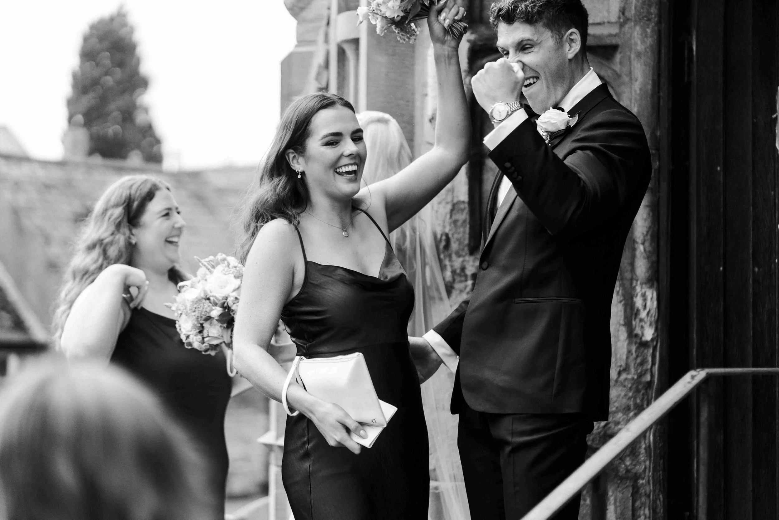 Groom is pouching the air while a bridesmaid cheers and smiling at the Halfmoon Farm Wedding in Rutland