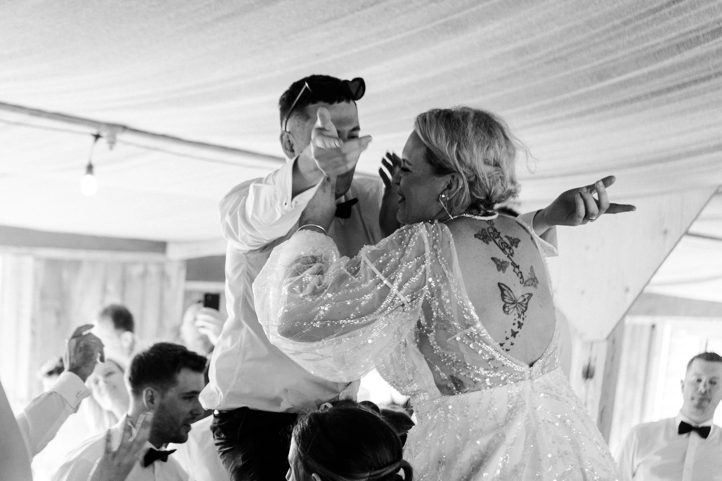 Wedding couple on guests' shoulders facing each other smiling at a rhyse farm wedding