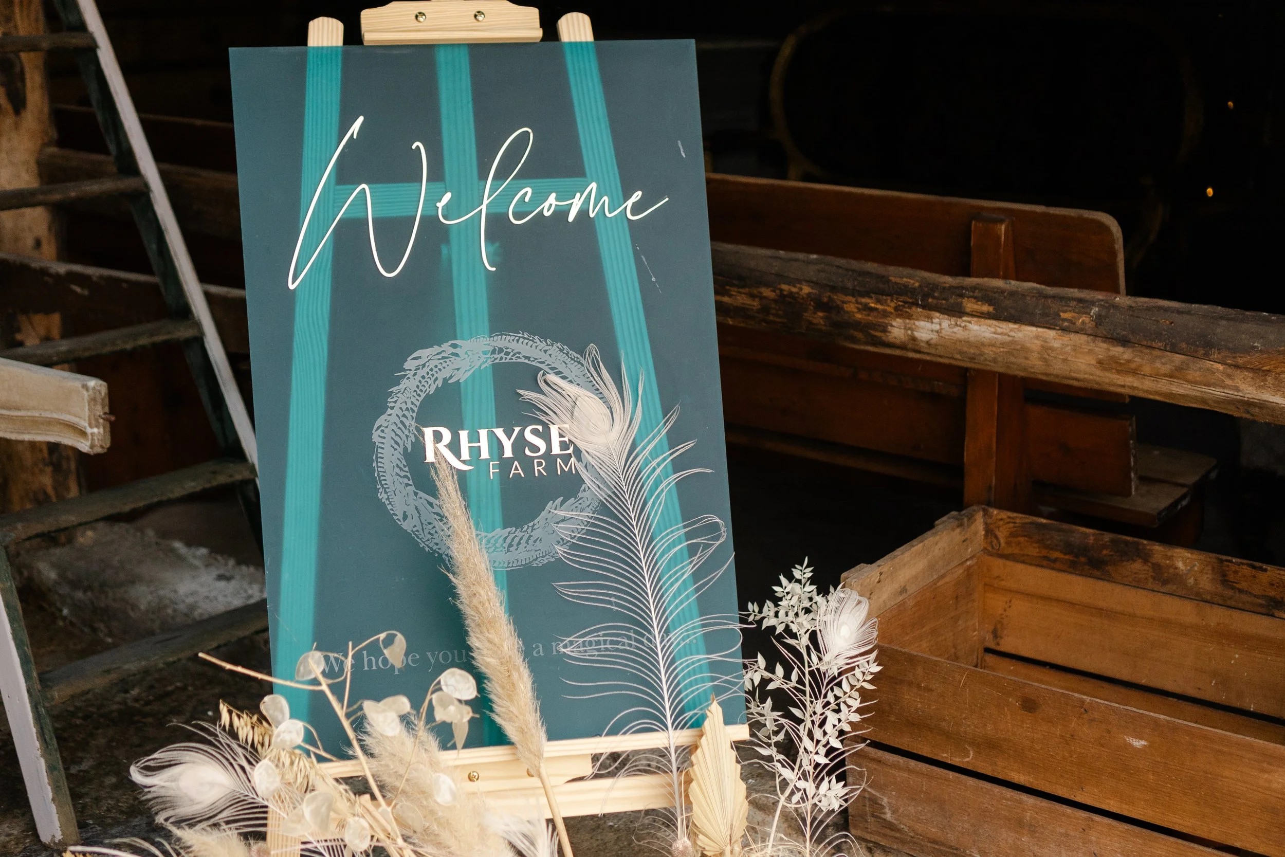 Welcome sign to a Worcestershire wedding photography on a easel with flowers arranged below at a rhyse farm wedding