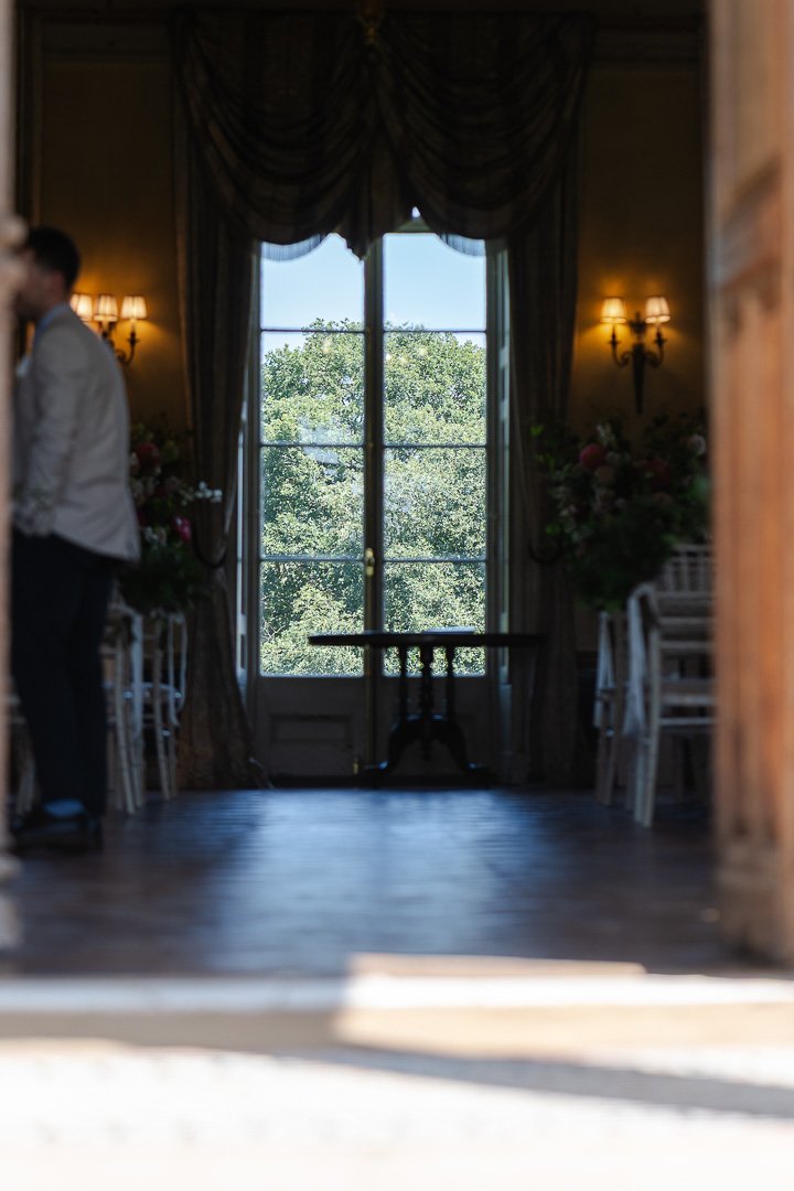 A view through a window at the back of the ceremony room from the front door of Hampton Court House at a London Wedding,