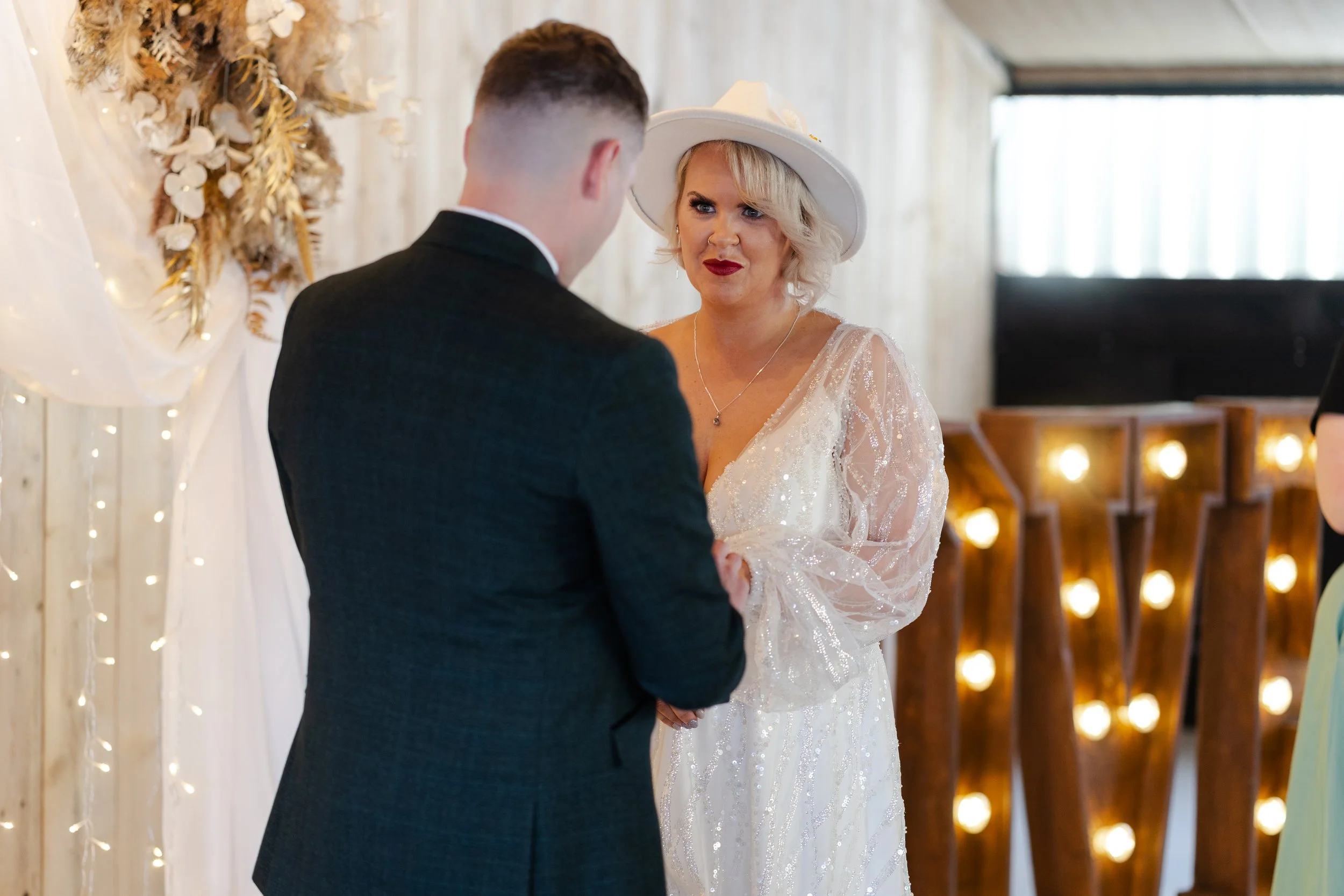 Wedding couple at the front of the ceremony, facing each other and holding hands doing their vows at a rhyse farm wedding