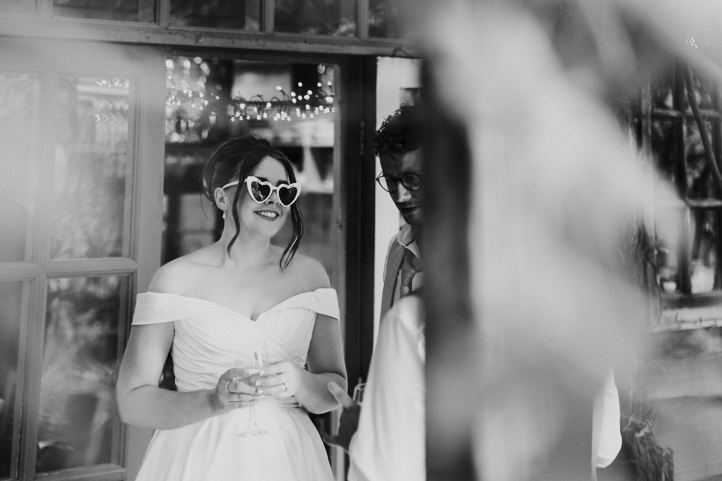 Bride wearing Heart Shape sunglasses and smiling at a Worton Kitchen Garden, Oxfordshire Wedding.