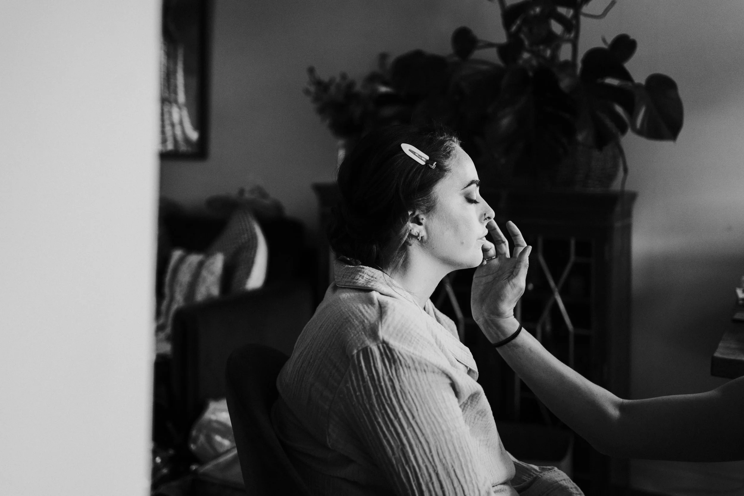 Bridemaids with her eyes closed getting her makeup done before a Worton Kitchen Garden, Oxfordshire Wedding