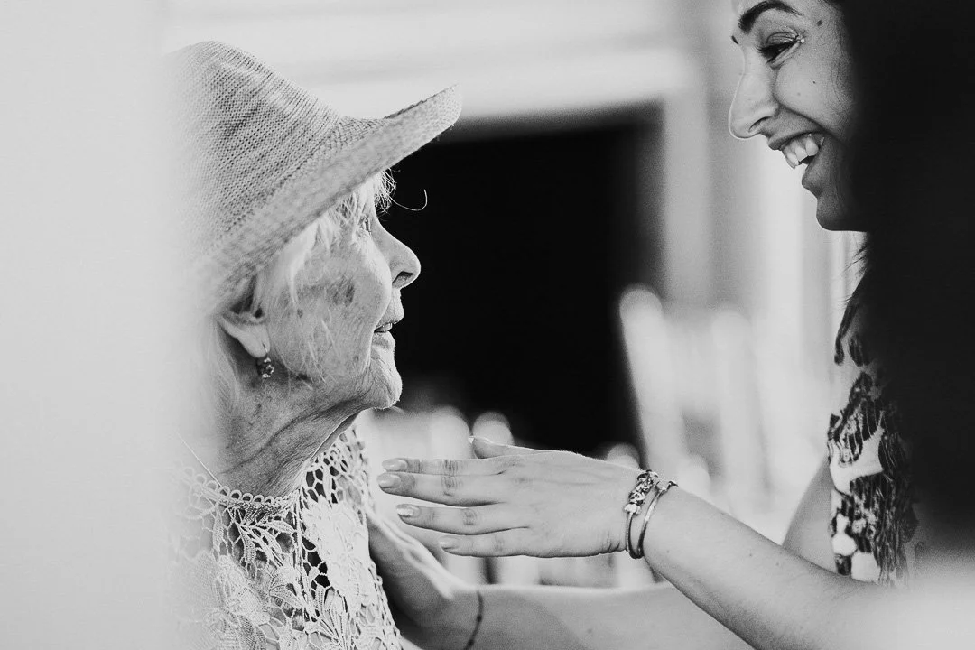 Guest greeting the Bride's Grandma, who is wearing a straw hat at a Hampton Court House Wedding