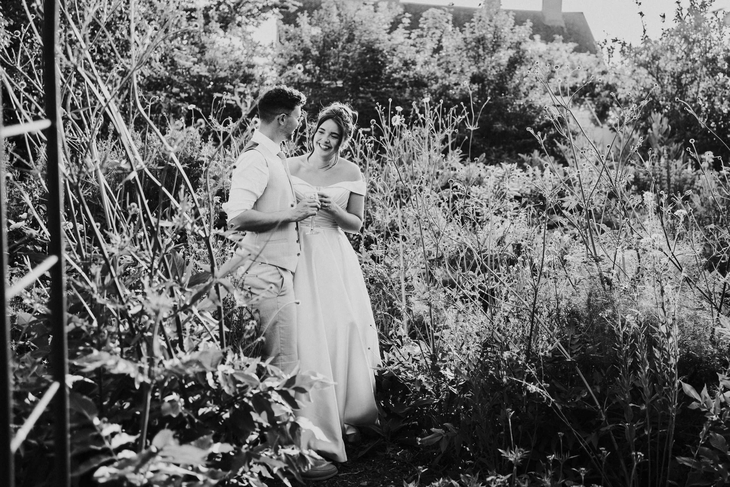 Wedding couple within the flowers garden looking at each other at a Worton Kitchen Garden, Oxfordshire Wedding.