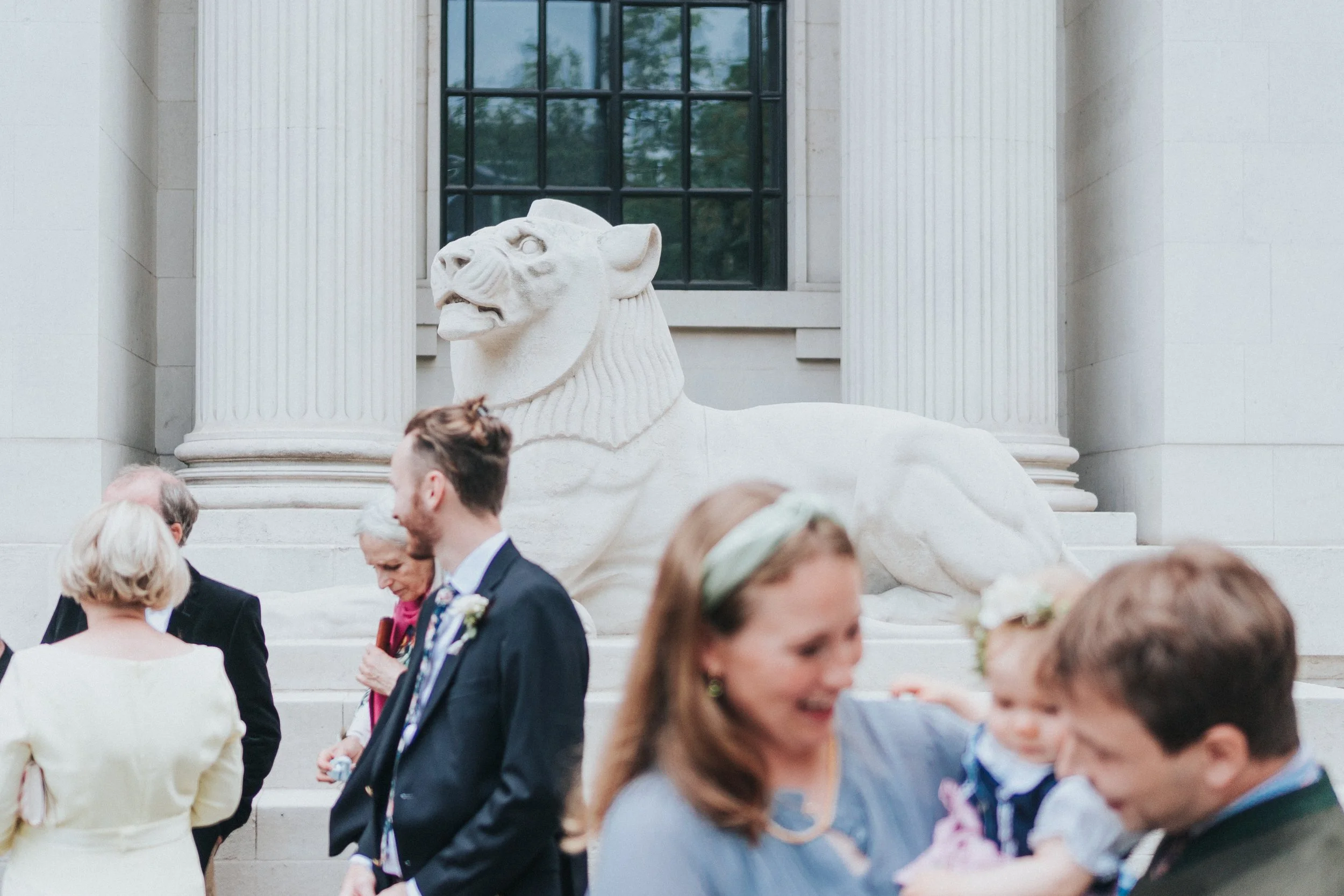 Guests mingling outside the town hall with the iconic lion in the background before a Old Marylebone Town Hall Wedding