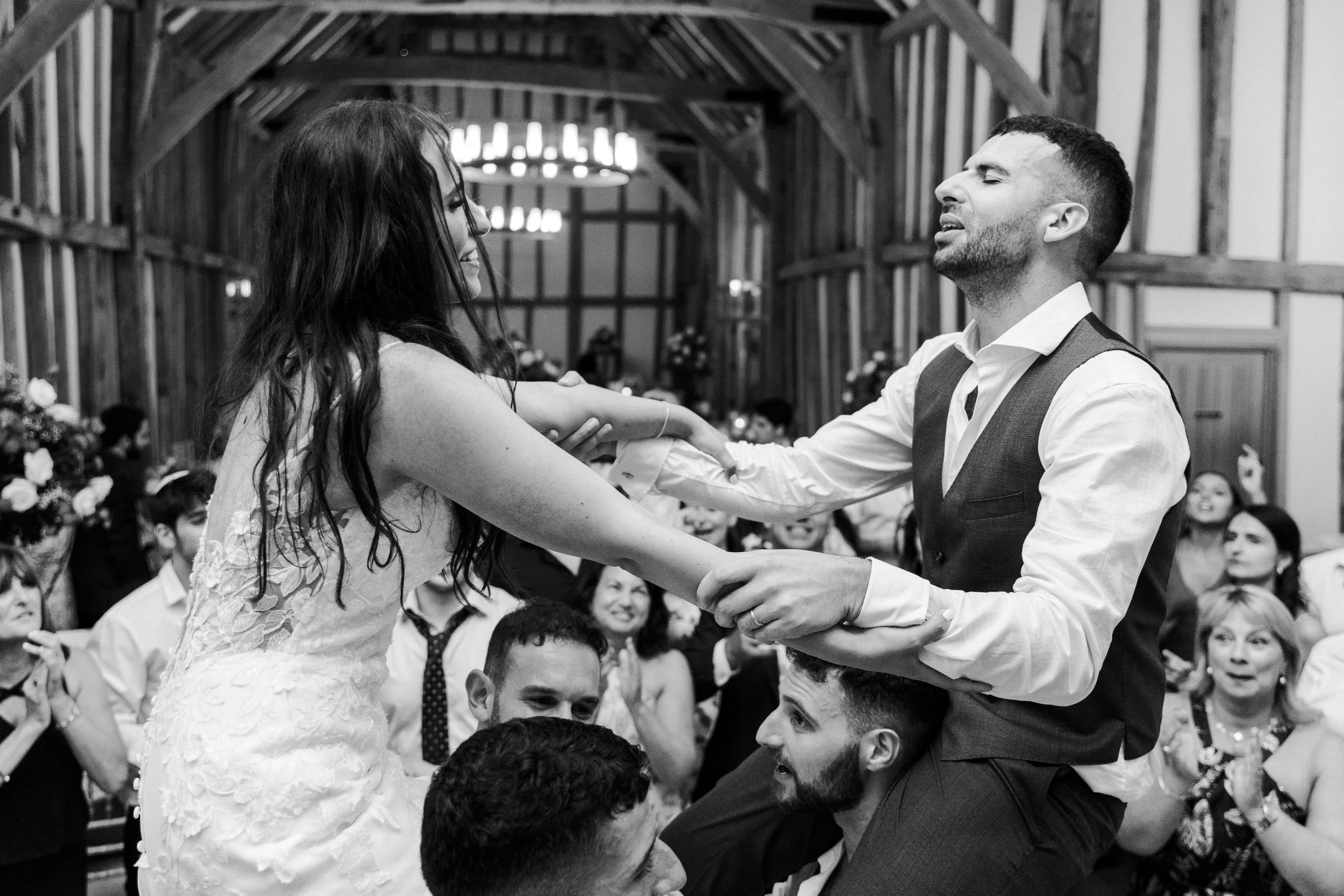 Wedding couple hoisted up on chair holding arms and smiling at a Micklefield Hall Wedding