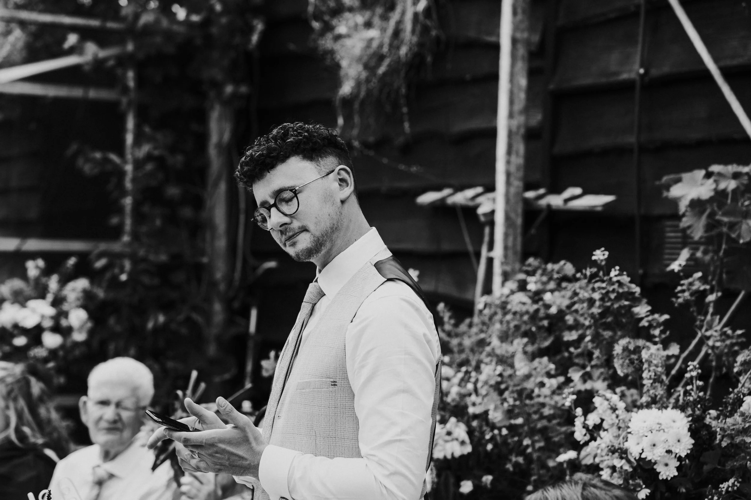 Groom standing at the Wedding reception dinner table, eyes closed at a Worton Kitchen Garden, Oxfordshire Wedding.