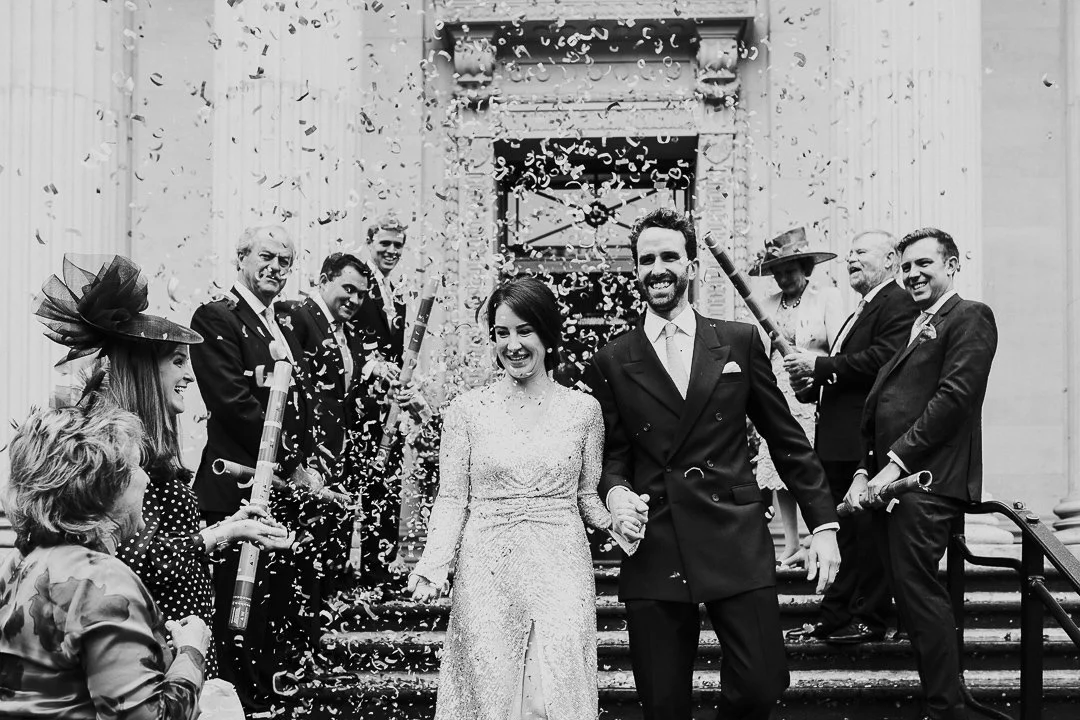 Wedding couple smiling at the end of the confetti line at the bottom of the steps at the Old Marylebone Town Hall Wedding.