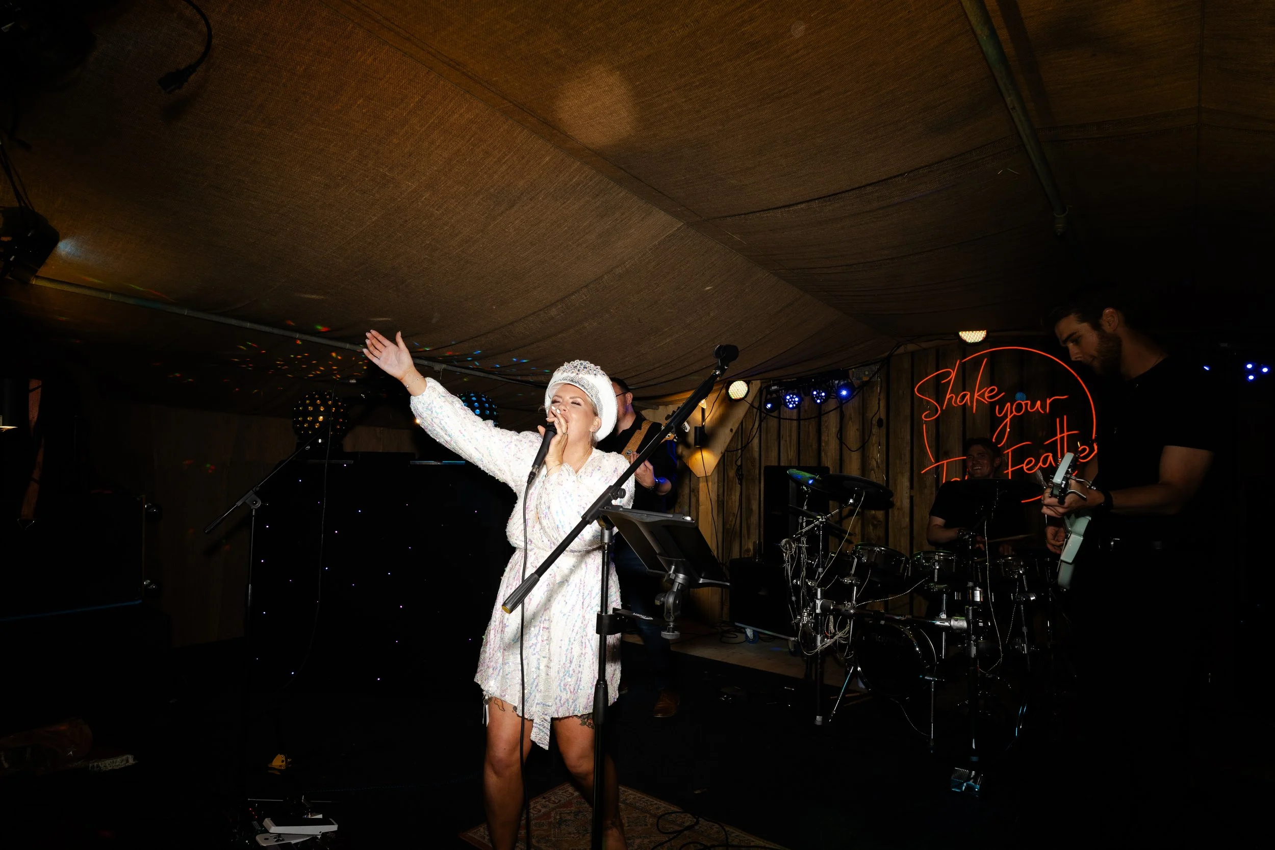 Bride on stage at wedding reception singing with a microphone at a rhyse farm wedding