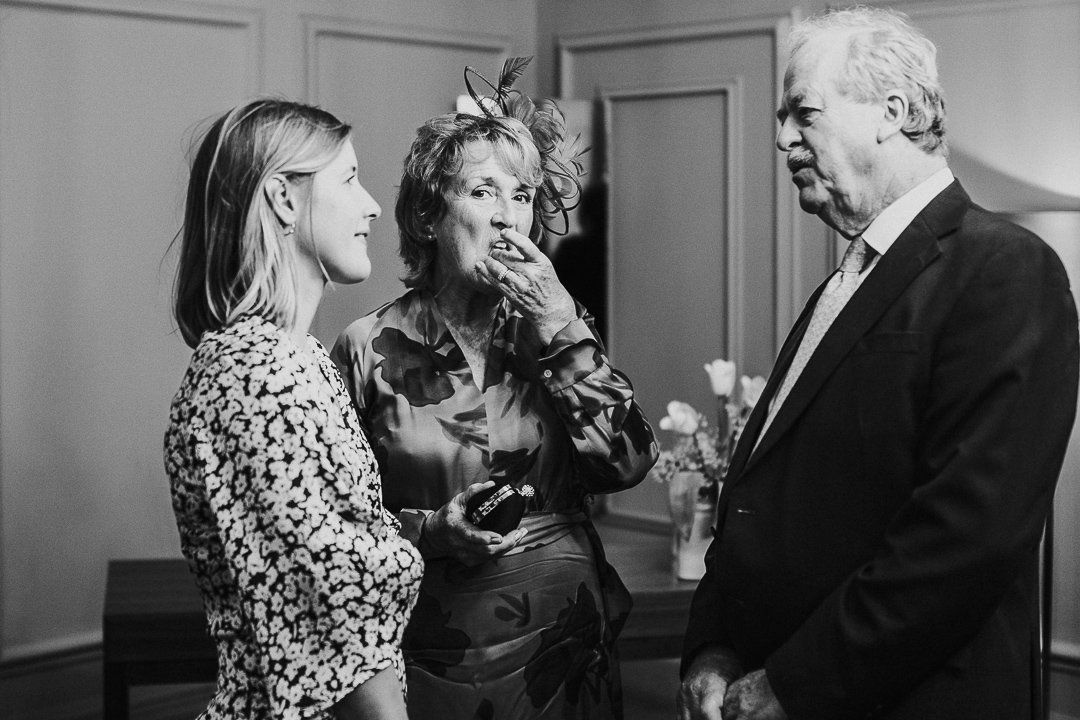 guest speaking to groom's parents while Groom's mum looks at the camera in the ceremony room at the Old Marylebone Town Hall Wedding