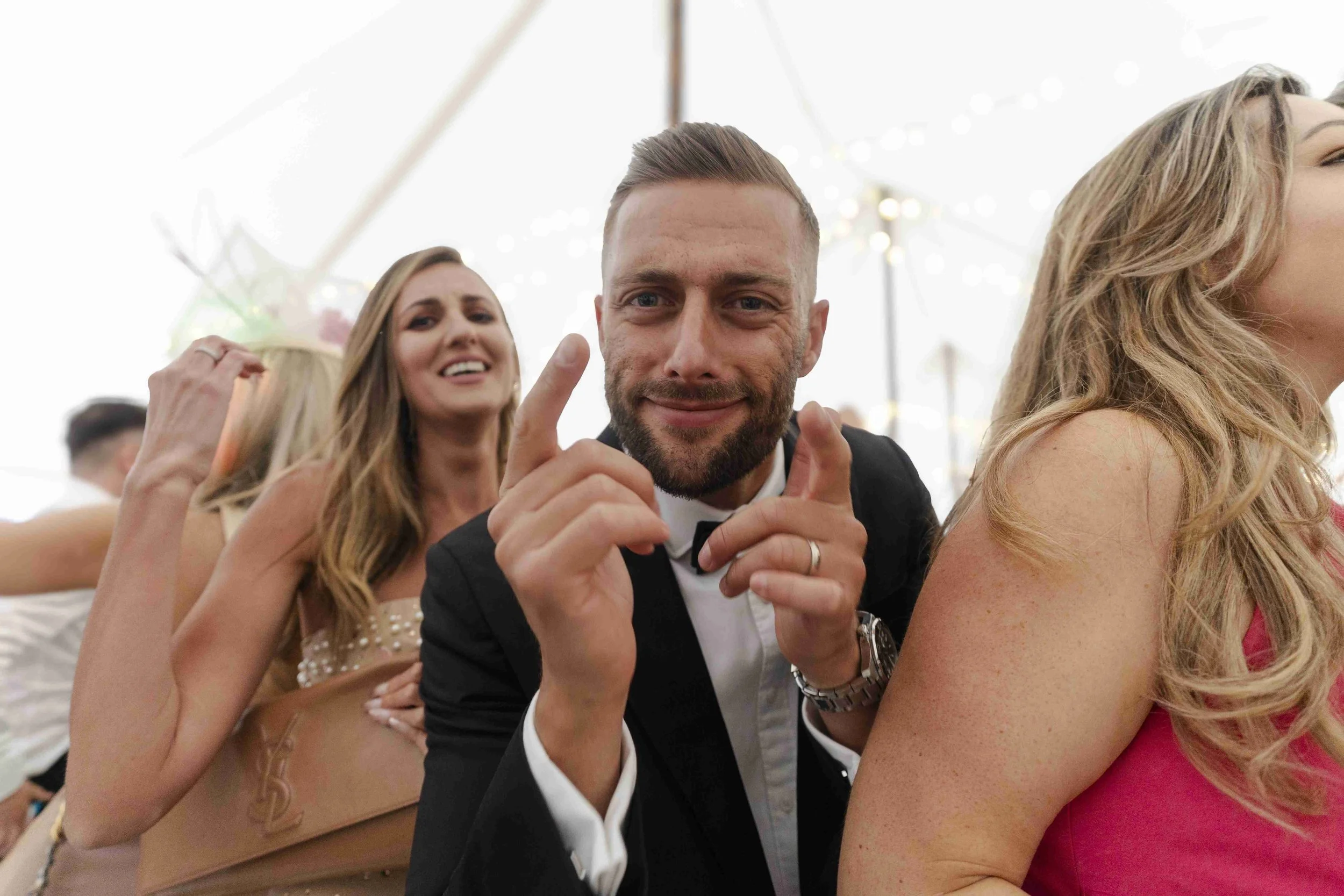 One male wedding guest pointing with two fingers at the camera at the Halfmoon Farm Wedding in Rutland